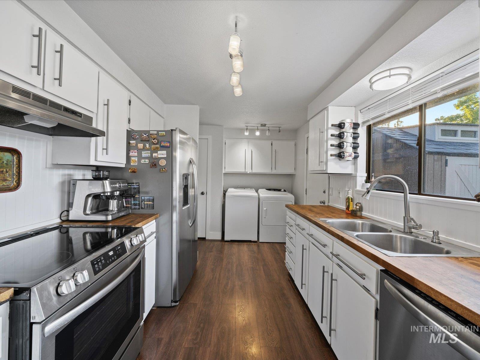 Kitchen with stainless steel appliances, wooden counters, white cabinetry, dark wood-style floors, and under cabinet range hood