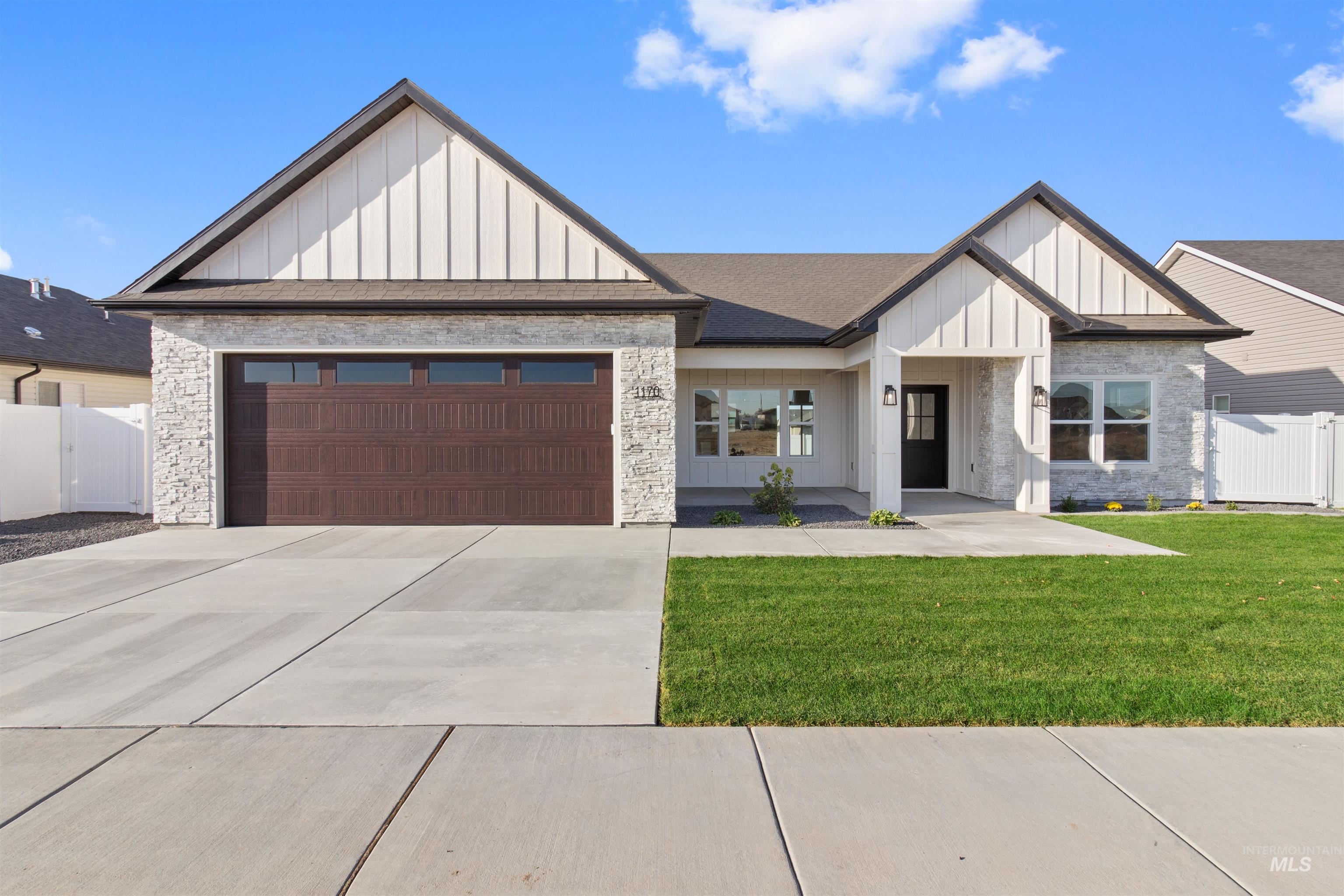 View of front facade with board and batten siding, an attached garage, concrete driveway, and stone siding