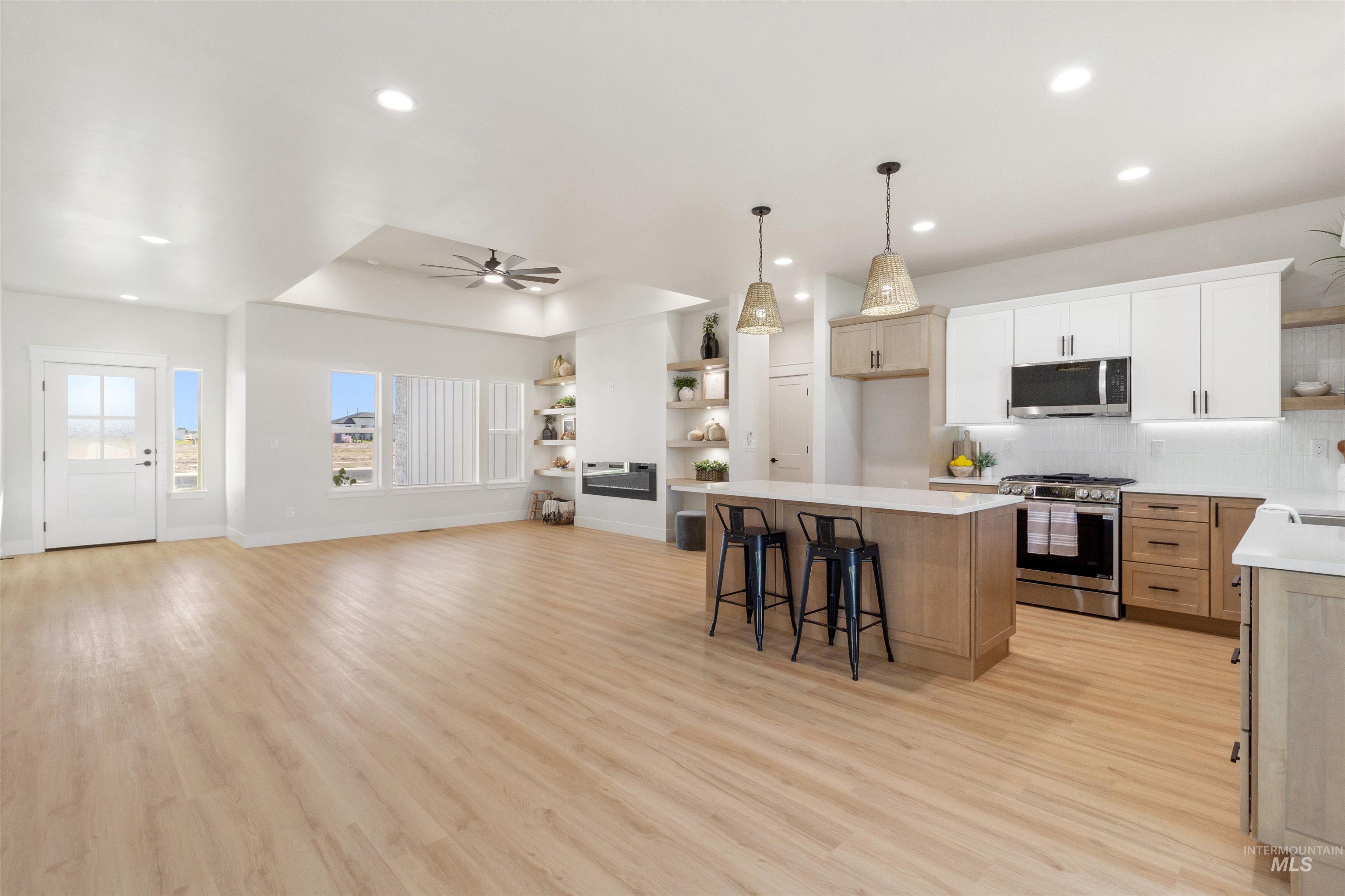 Kitchen featuring open shelves, a tray ceiling, stainless steel appliances, a breakfast bar, and hanging light fixtures
