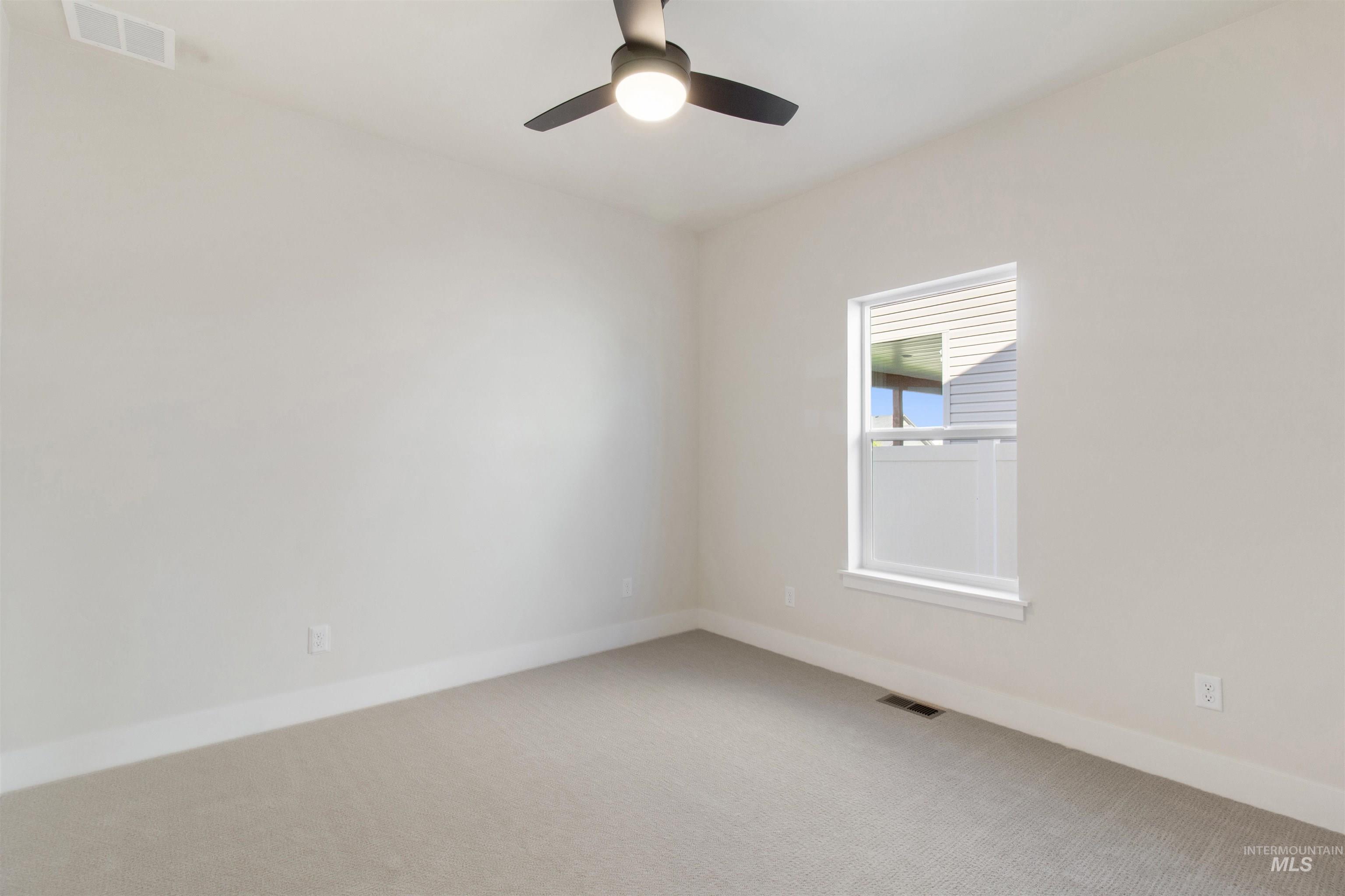 Empty room with light colored carpet and ceiling fan