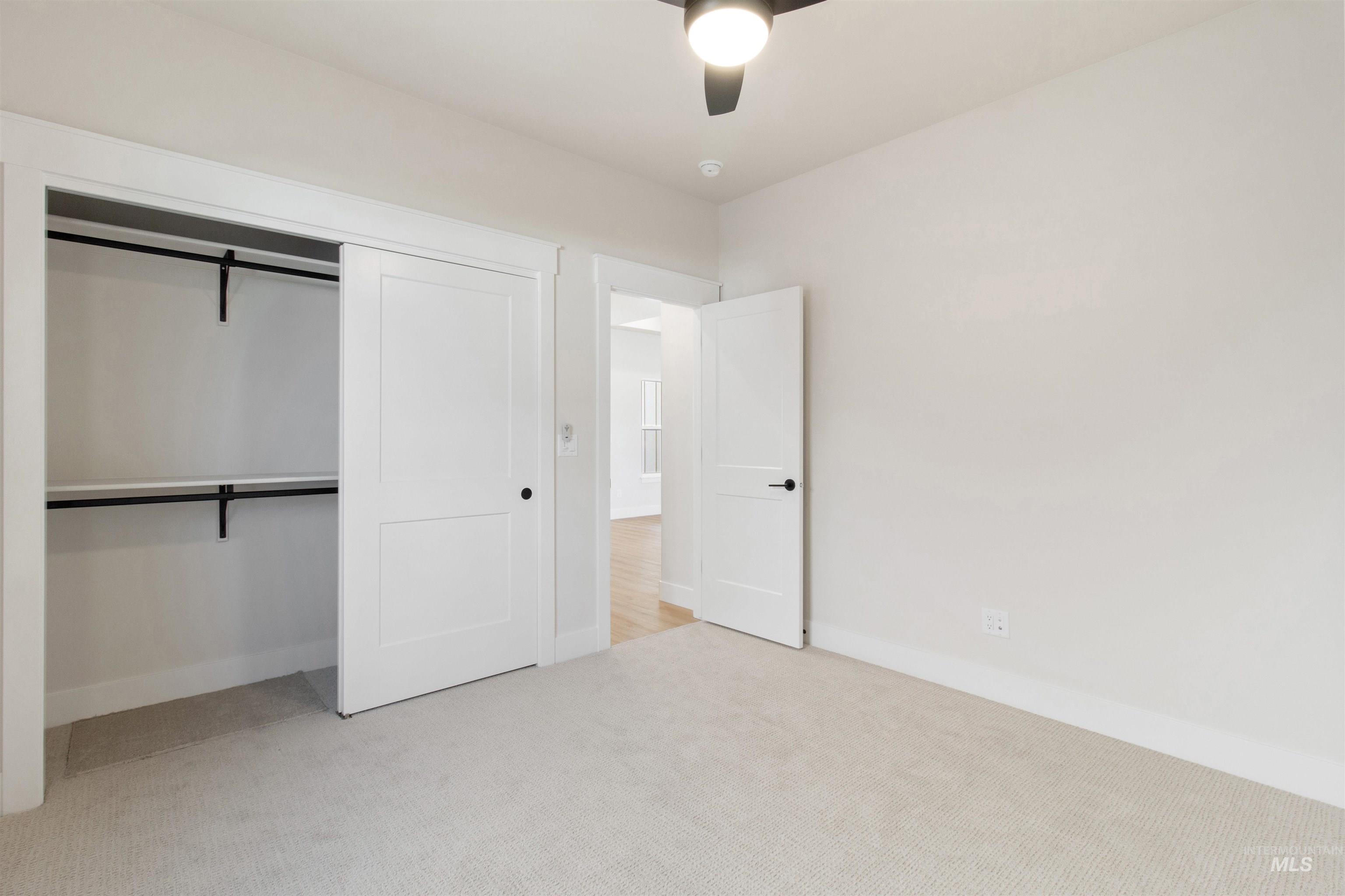 Unfurnished bedroom with light carpet, a closet, and a ceiling fan