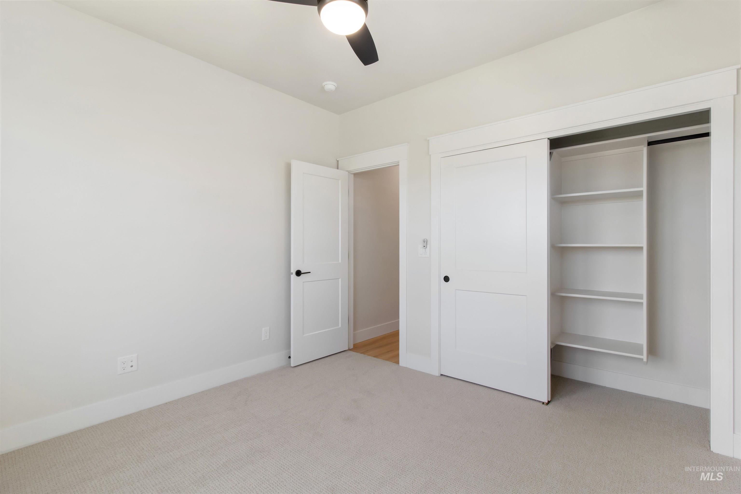 Unfurnished bedroom featuring light carpet, a closet, and ceiling fan