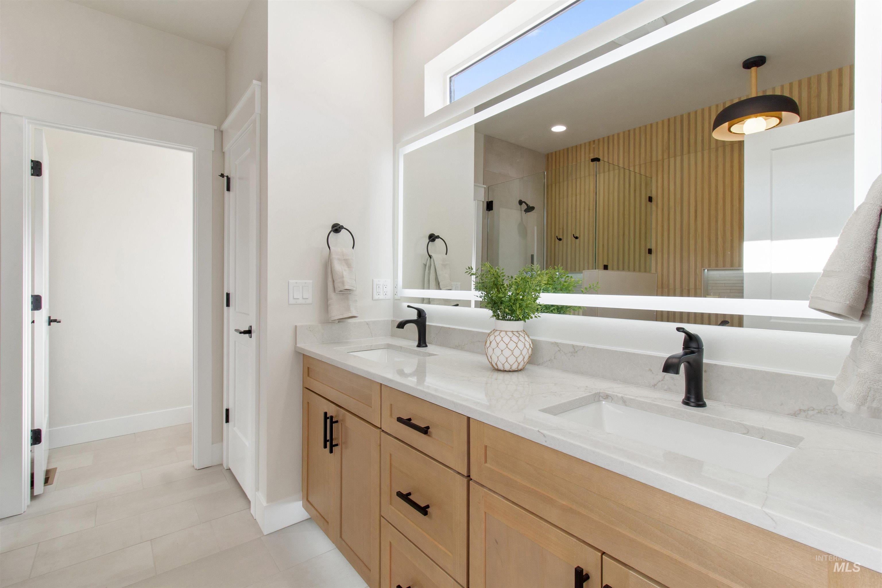 Full bathroom with a shower stall, double vanity, and light tile patterned floors