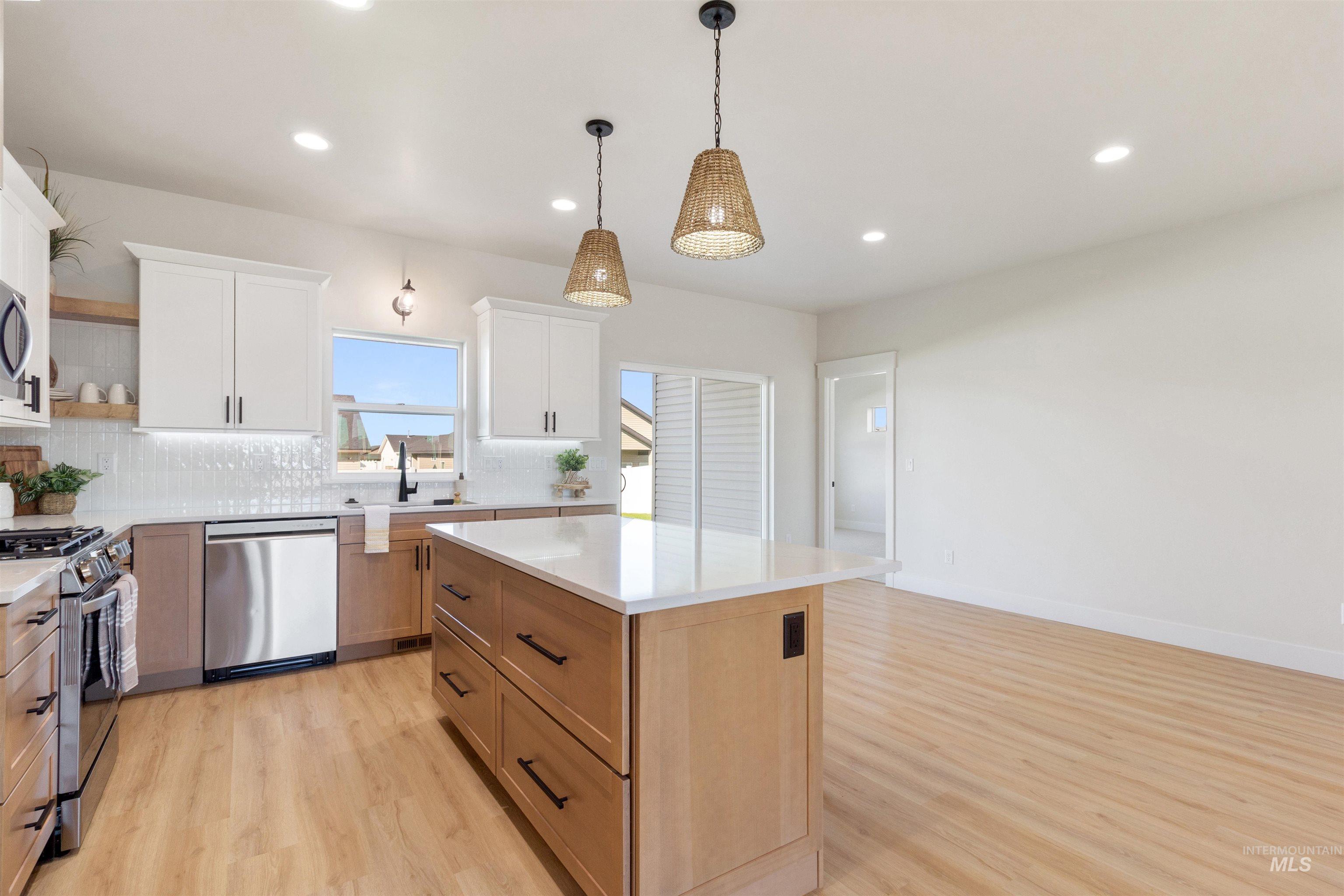 Kitchen with appliances with stainless steel finishes, white cabinets, recessed lighting, backsplash, and light wood finished floors