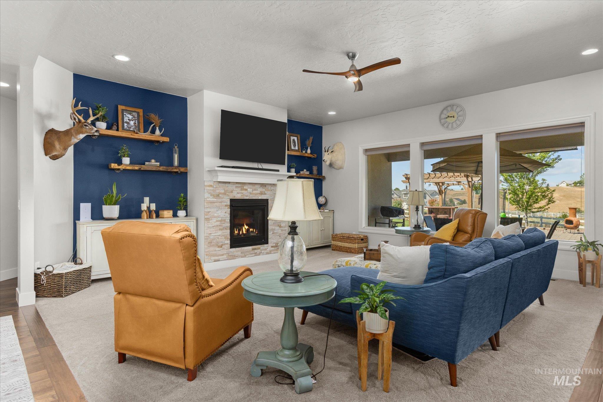 Living area with light wood-style floors, recessed lighting, ceiling fan, a textured ceiling, and a stone fireplace