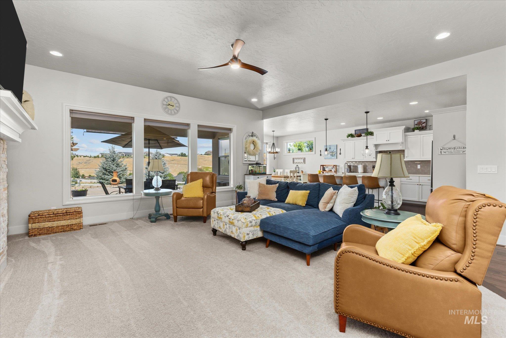 Living room with recessed lighting, a ceiling fan, light carpet, and a textured ceiling