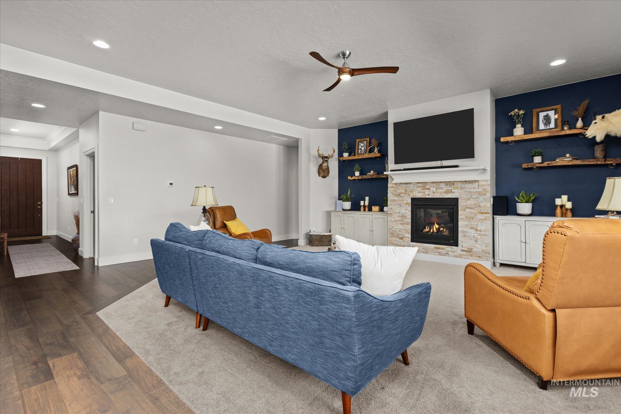 Living area featuring recessed lighting, ceiling fan, a stone fireplace, built in shelves, and a textured ceiling