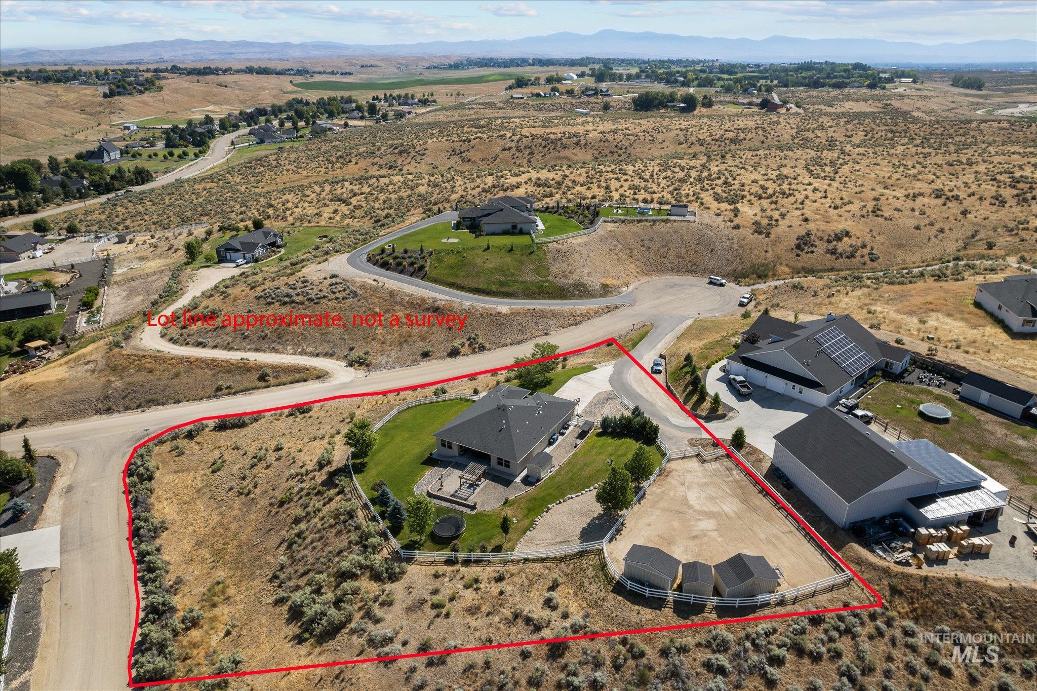 Aerial view of sparsely populated area with property boundaries highlighted and a mountainous background
