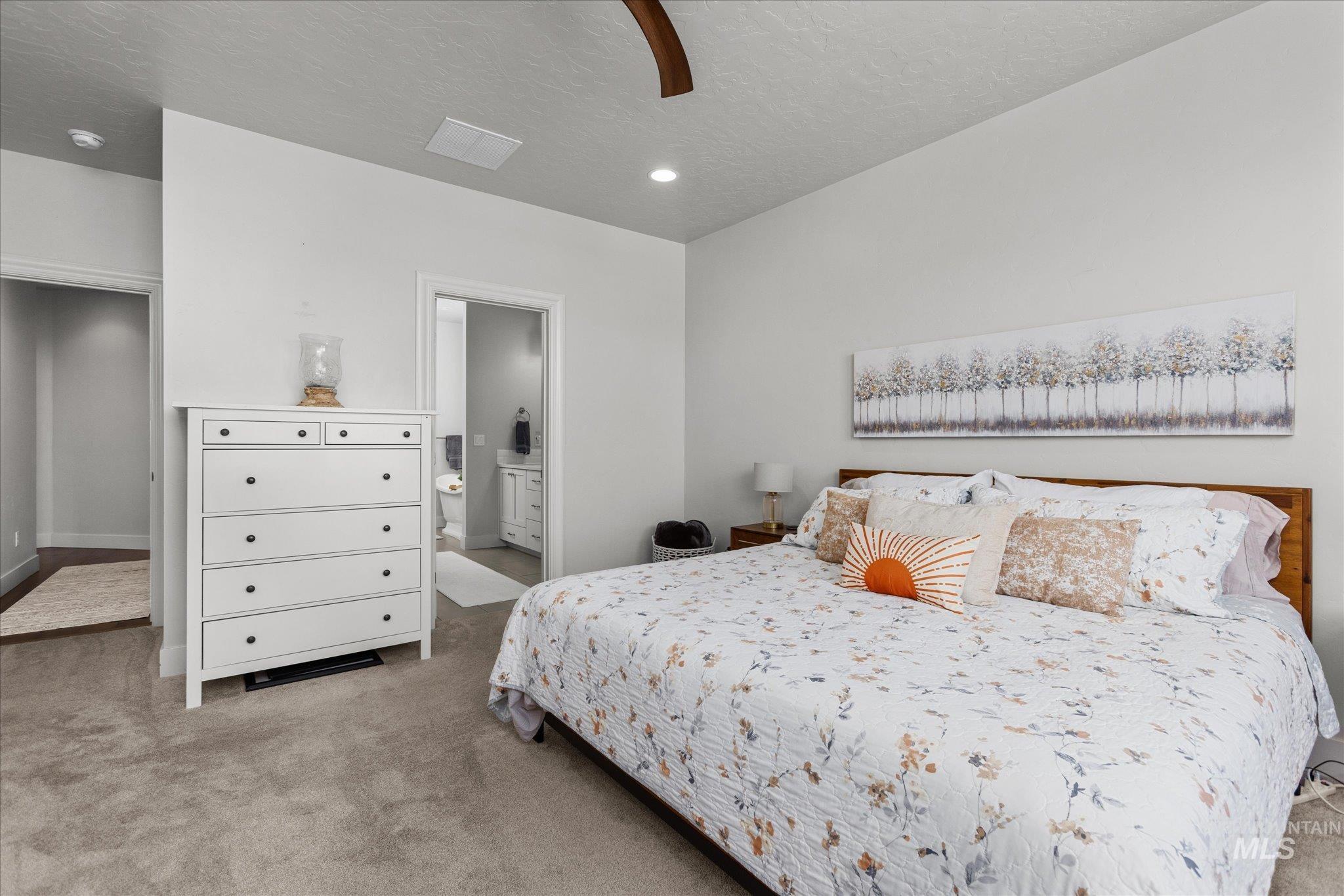 Carpeted bedroom with a textured ceiling, connected bathroom, a ceiling fan, and recessed lighting