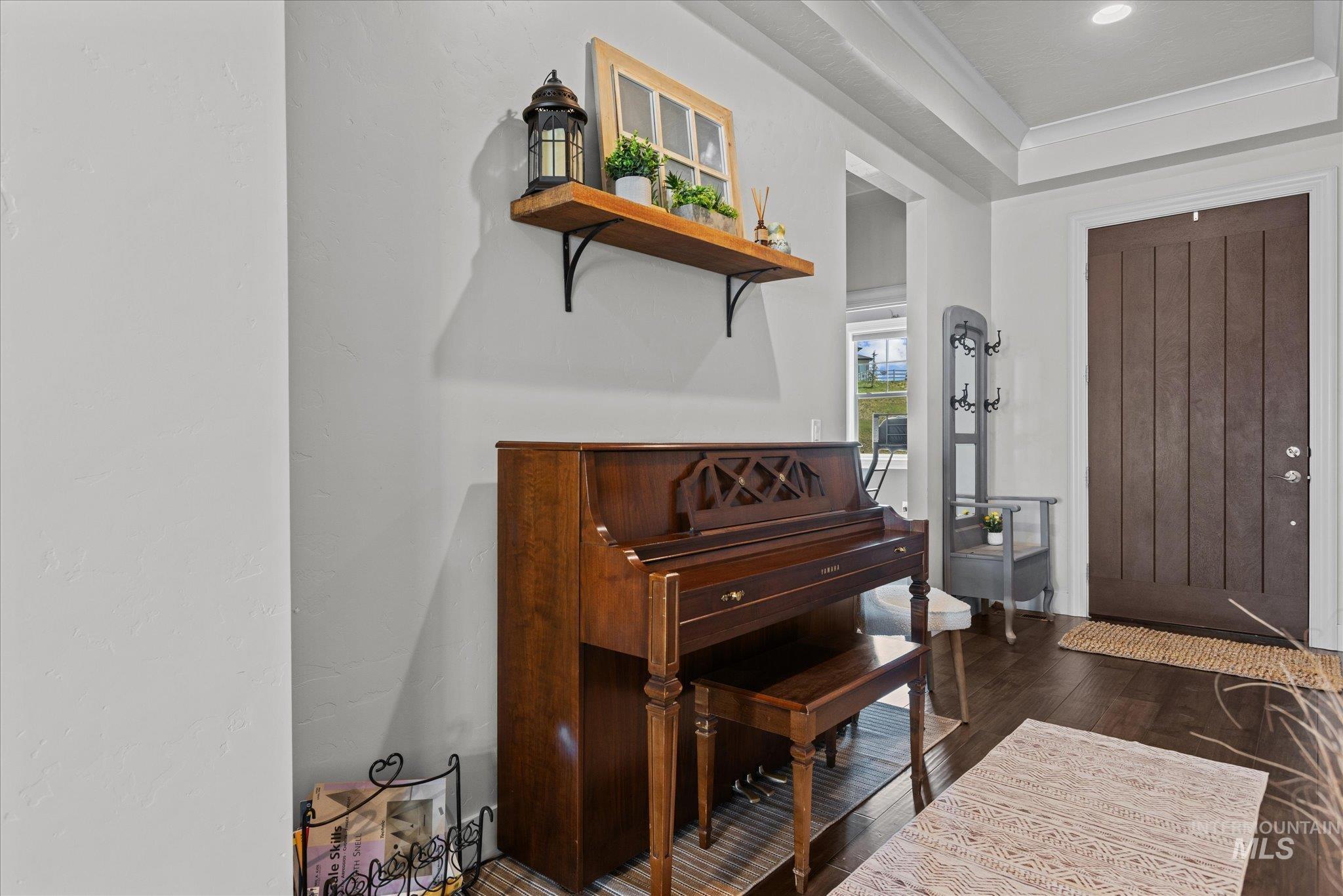 Foyer entrance featuring wood-type flooring, ornamental molding, and a raised ceiling