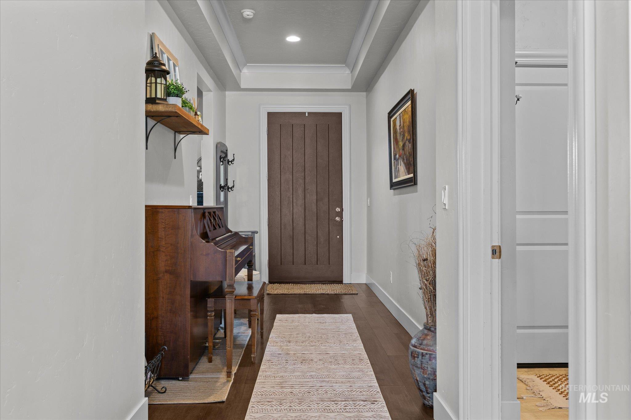 Foyer entrance with a raised ceiling, dark wood finished floors, and recessed lighting