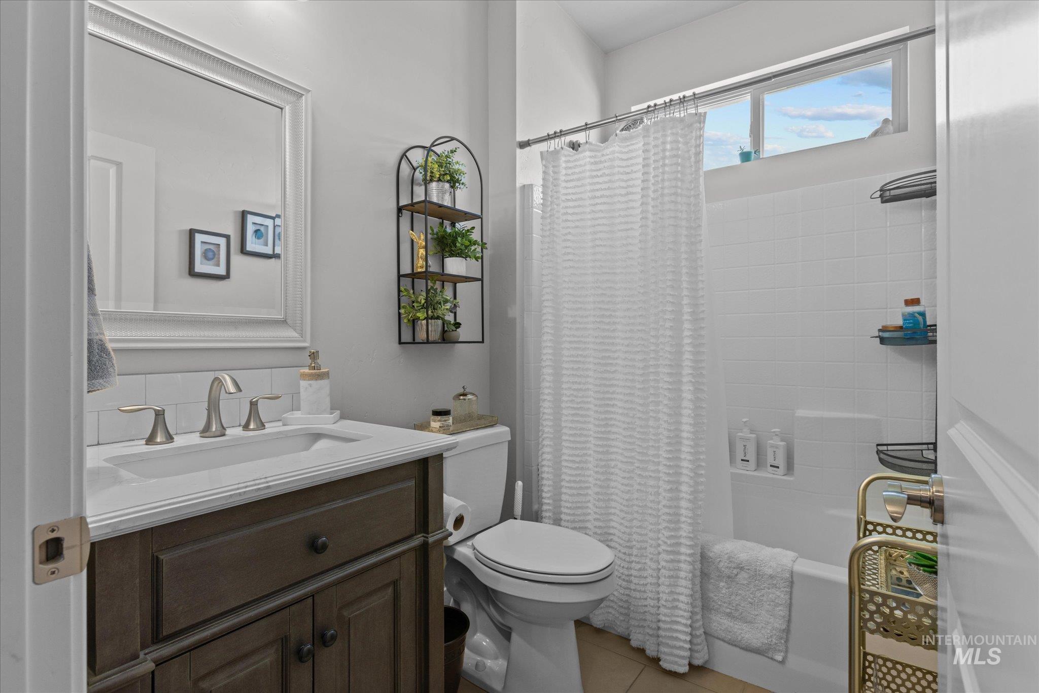 Full bathroom featuring vanity, shower / bath combo with shower curtain, and tile patterned floors