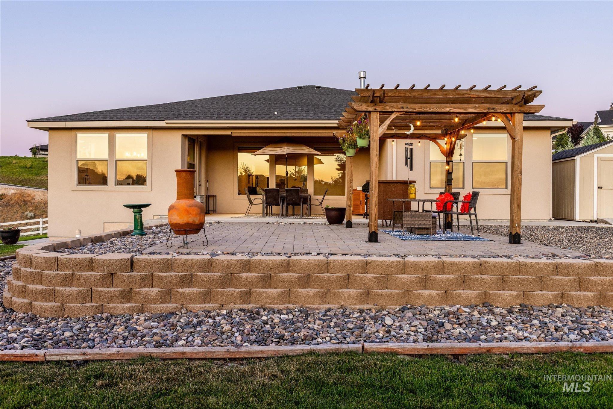 Back of property with a shed, stucco siding, a patio, and a shingled roof