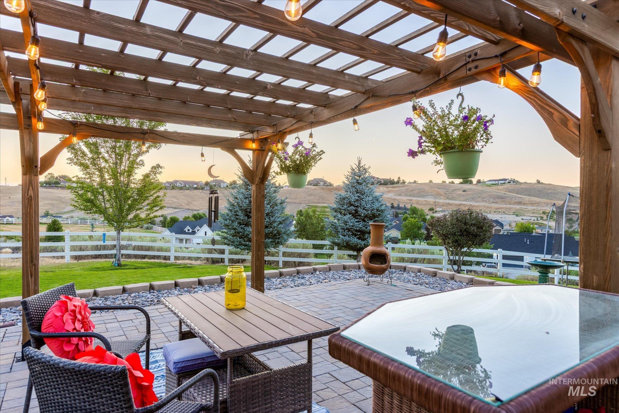 Patio terrace at dusk featuring a patio area, a pergola, a fenced backyard, and outdoor dining space