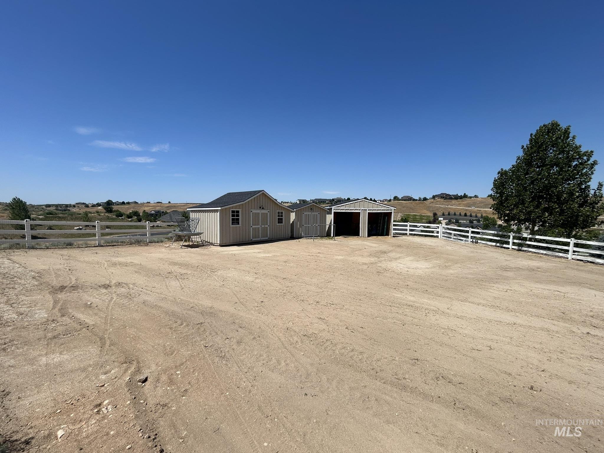 View of yard with a storage unit, a garage, a rural view, and driveway