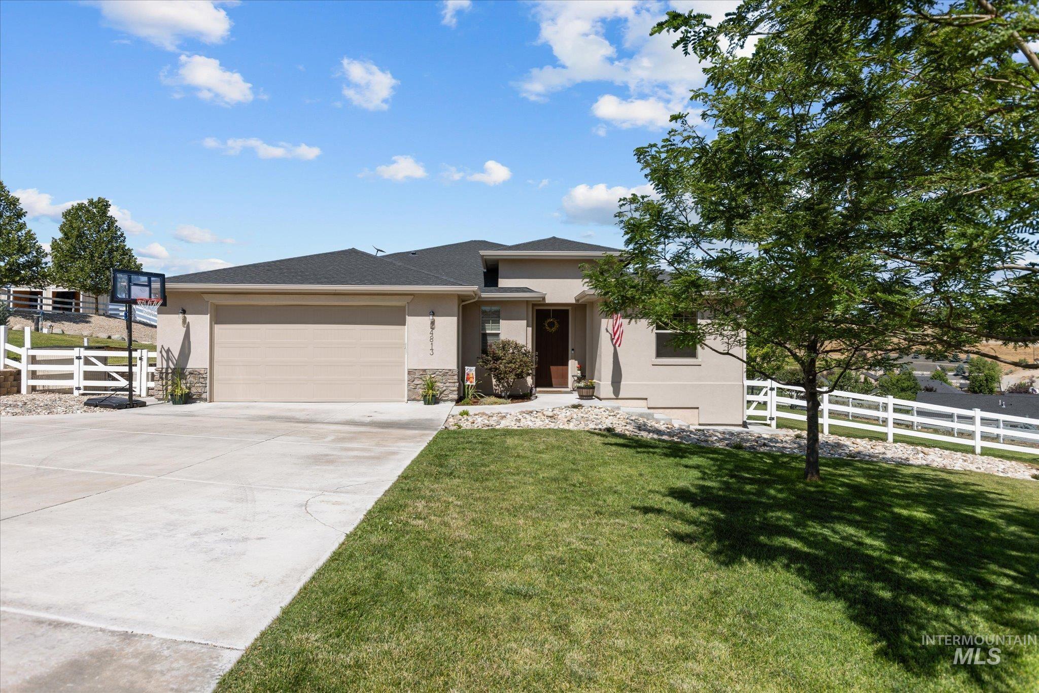 Prairie-style home with an attached garage, driveway, stone siding, stucco siding, and a shingled roof