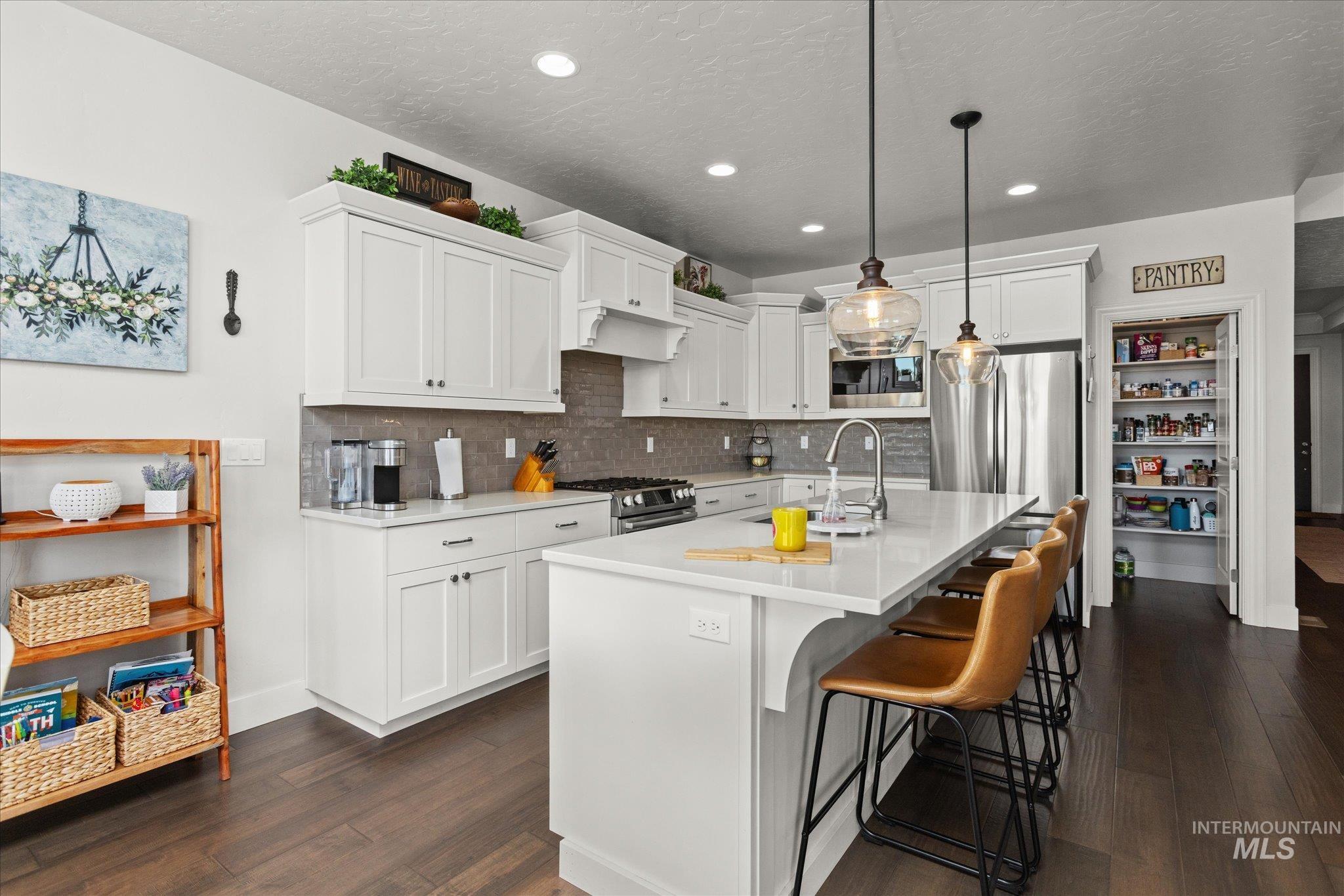 Kitchen with dark wood-style flooring, light countertops, white cabinets, recessed lighting, and a textured ceiling