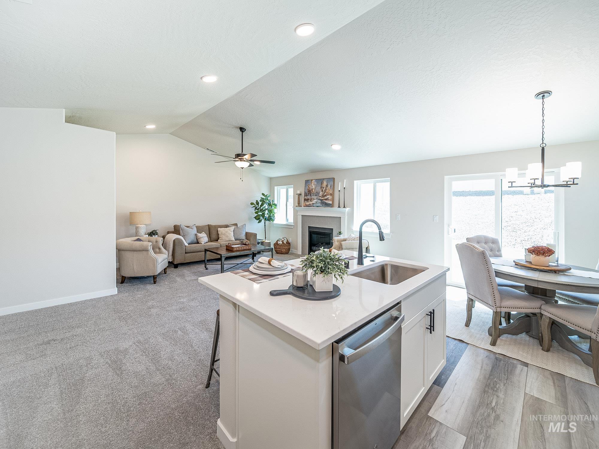 Kitchen with stainless steel dishwasher, a fireplace, a chandelier, white cabinetry, and light countertops