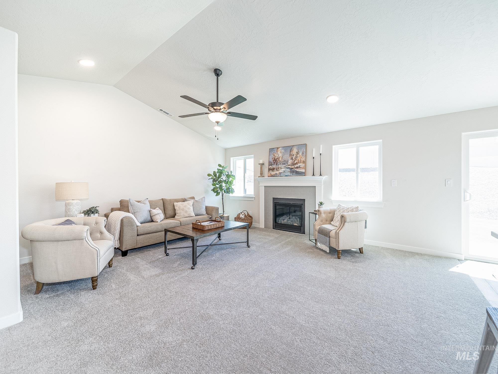 Living area with a glass covered fireplace, light carpet, lofted ceiling, and ceiling fan