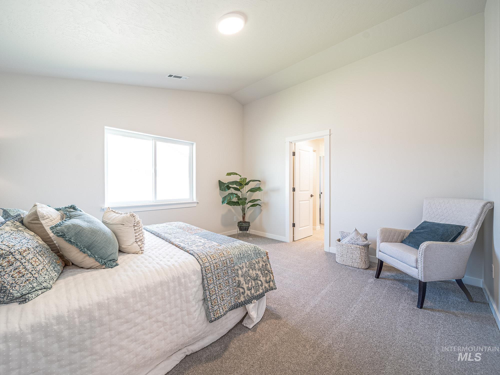 Carpeted bedroom featuring vaulted ceiling and baseboards