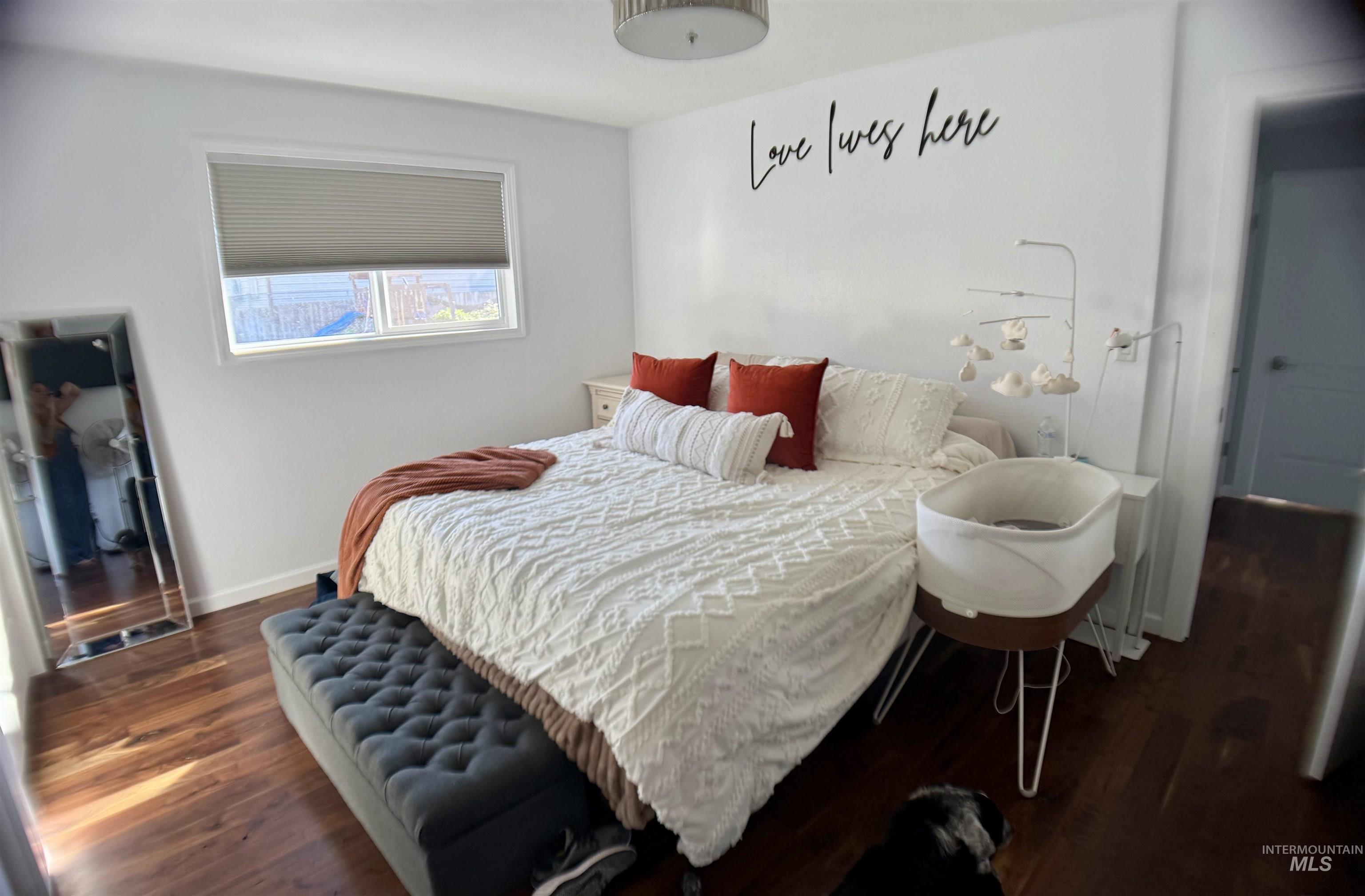 Bedroom with dark wood-type flooring and baseboards