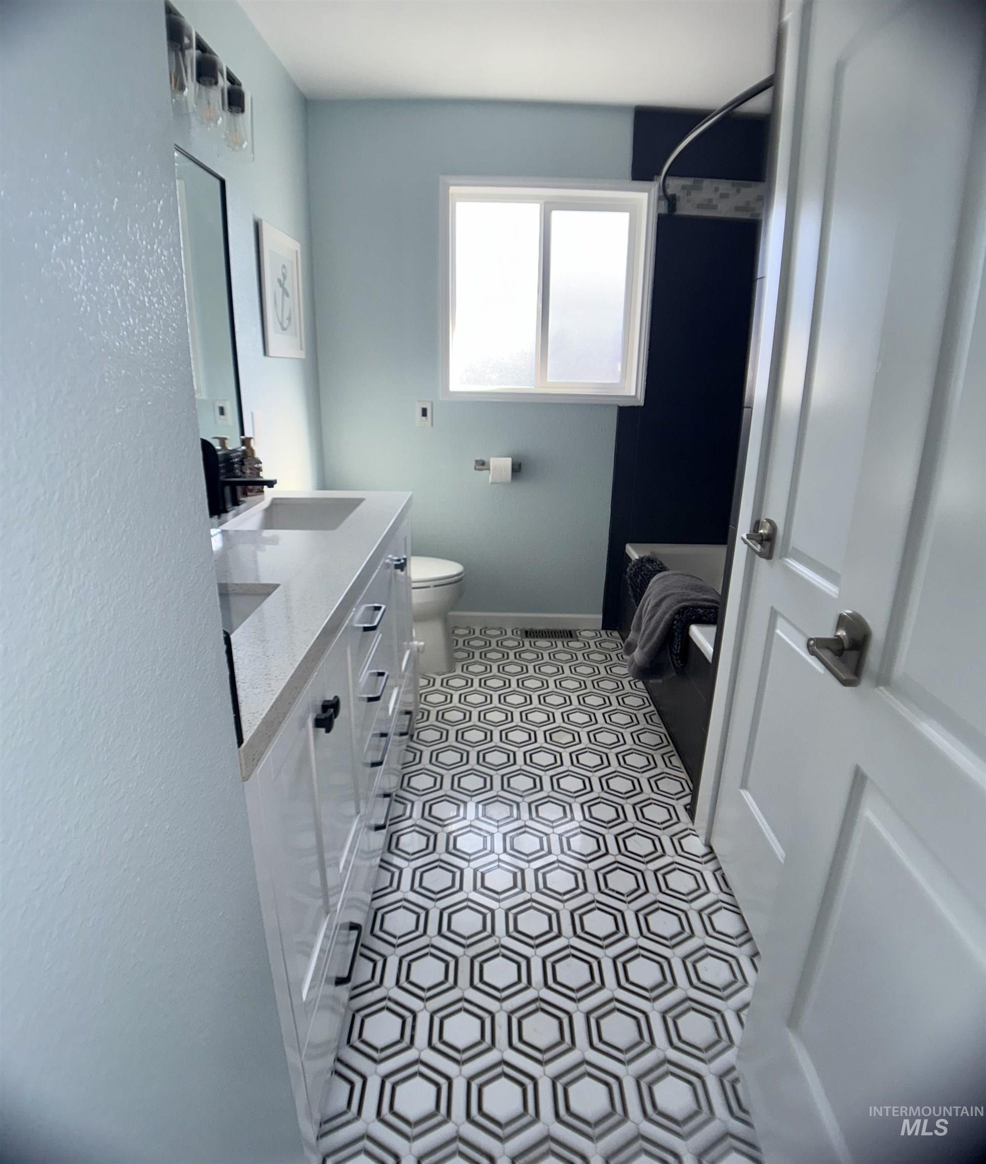 Full bath featuring vanity, light tile patterned floors, and shower / bath combo