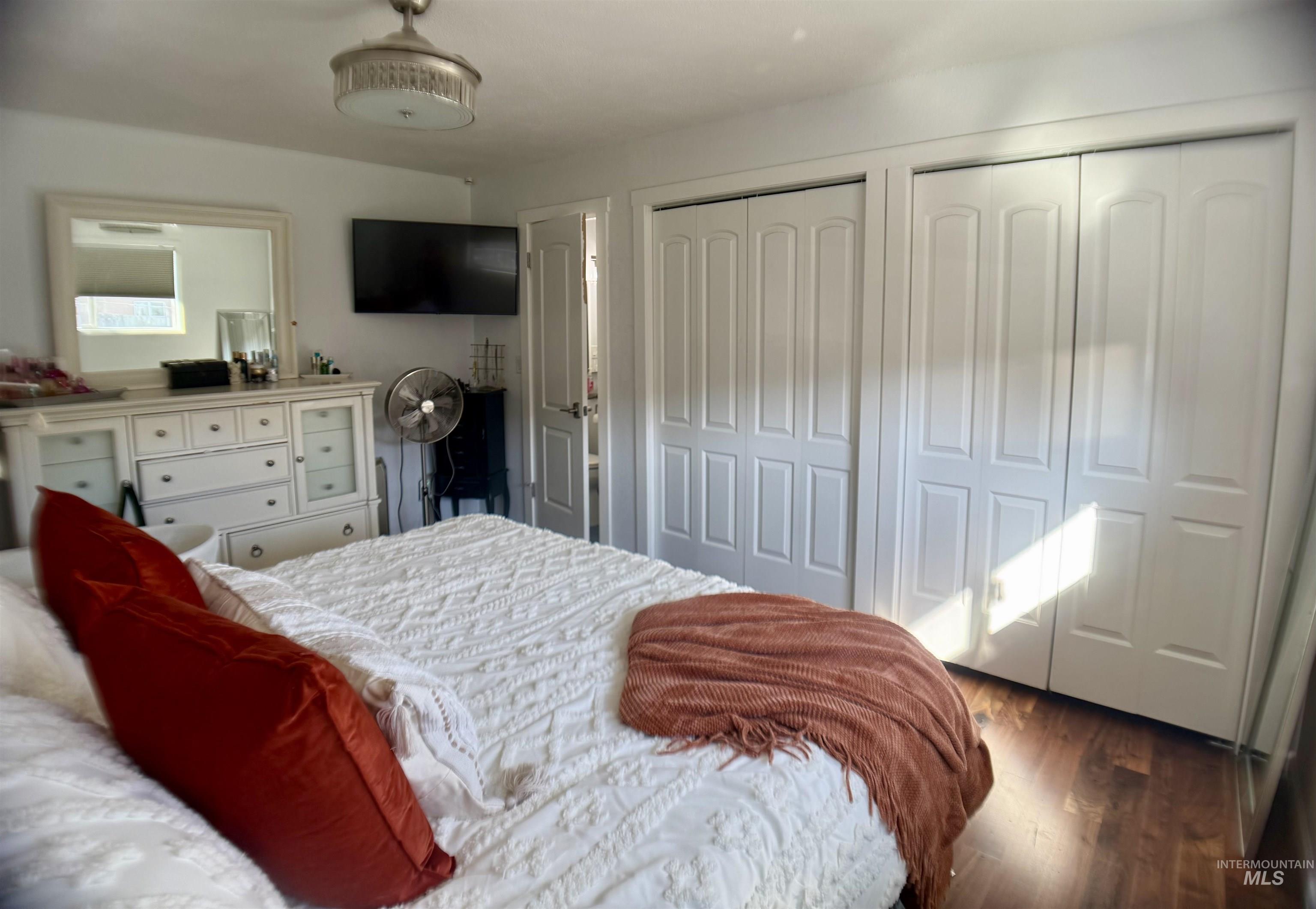 Bedroom with two closets and dark wood-style flooring