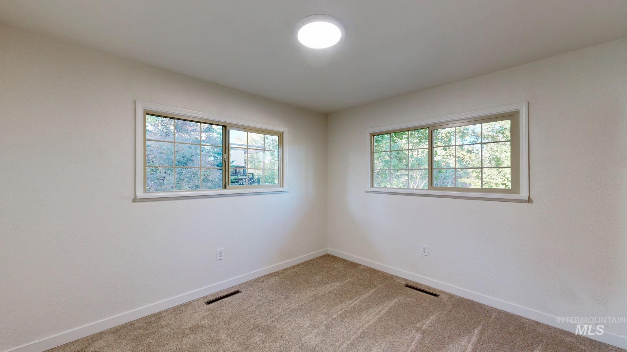 Empty room featuring light colored carpet and plenty of natural light