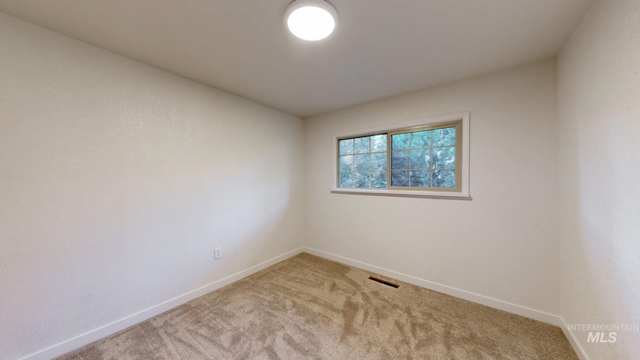 Spare room featuring light colored carpet and baseboards