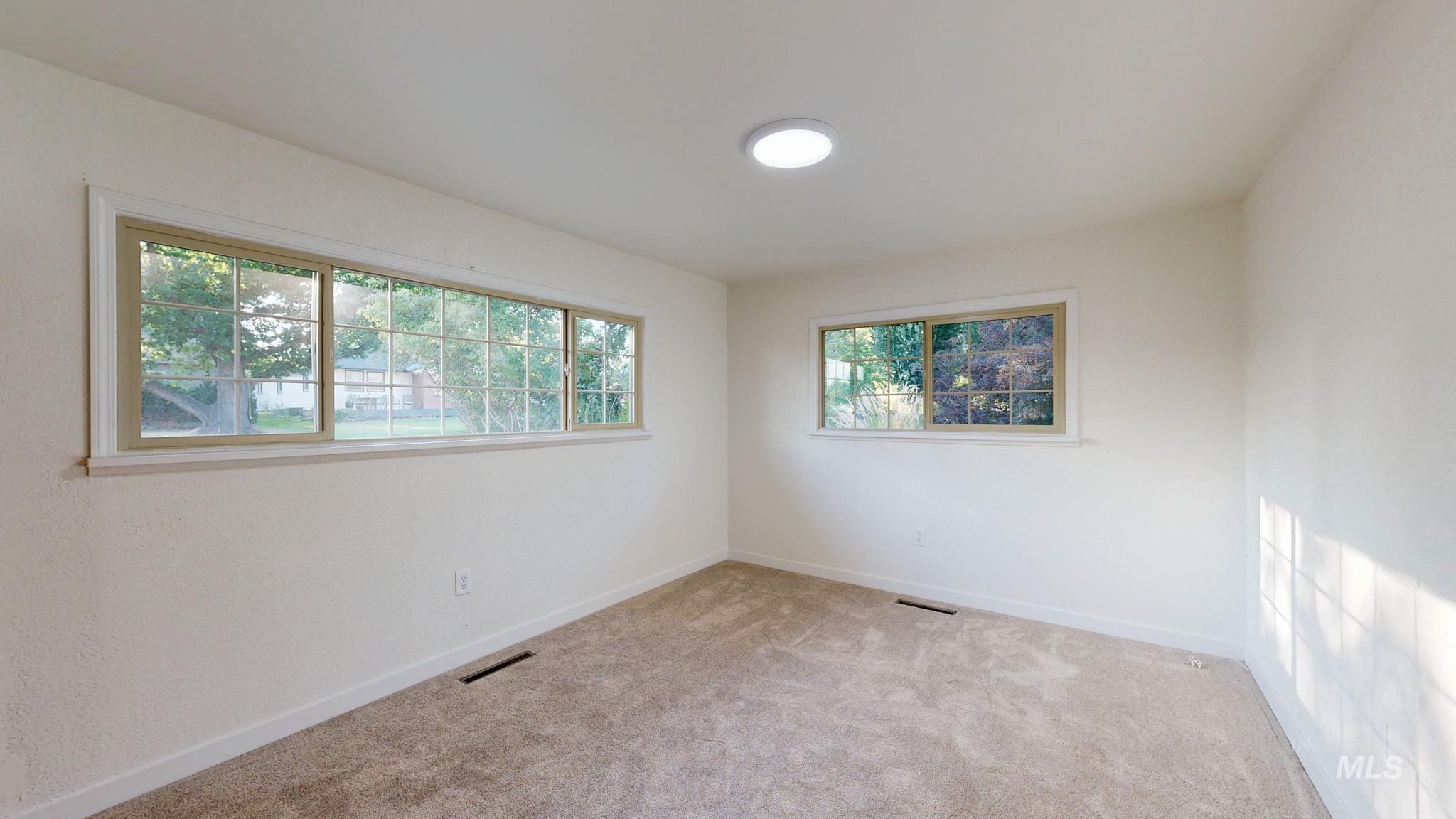 Empty room featuring light carpet and baseboards