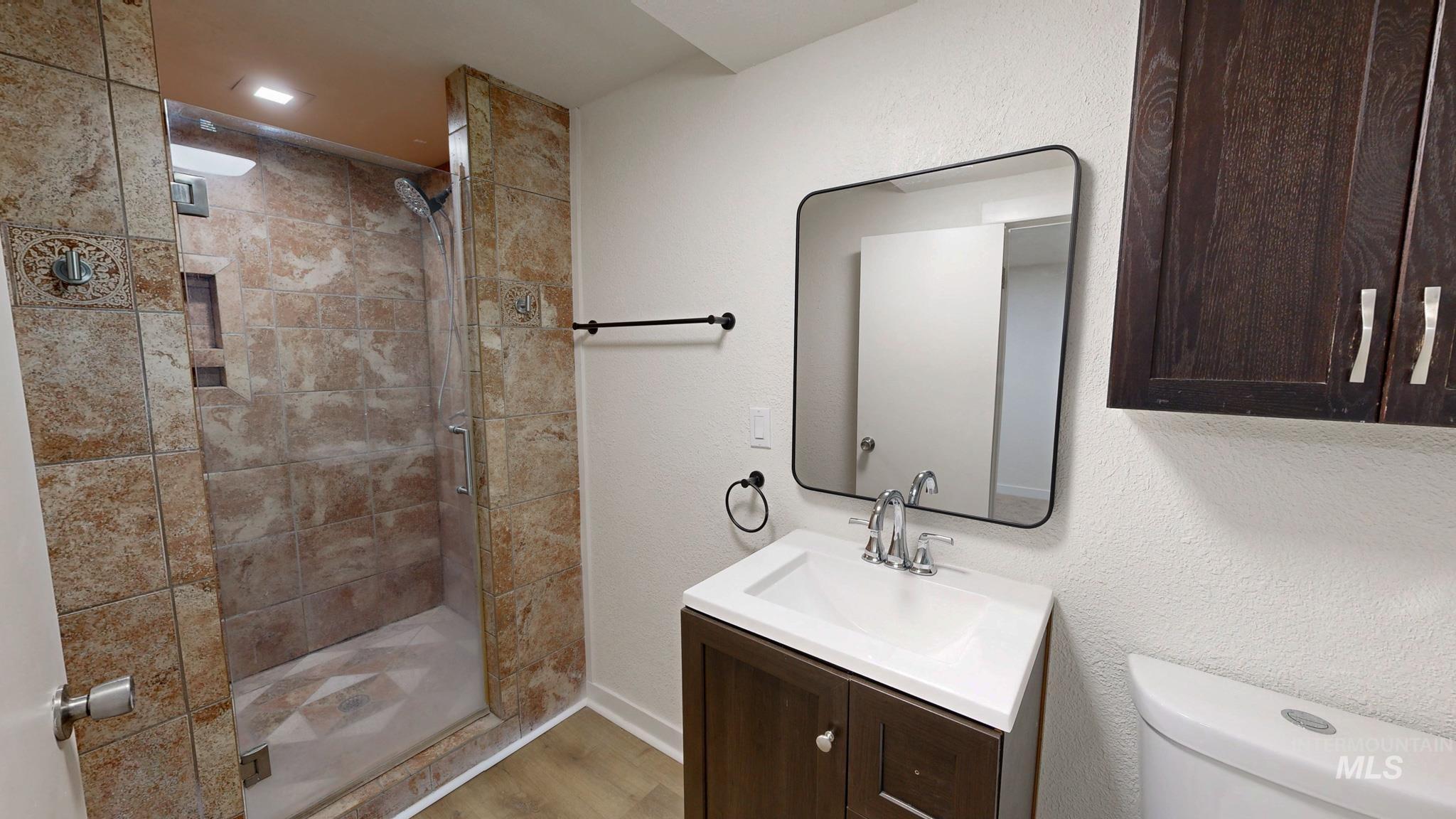Full bath featuring vanity, a stall shower, and a textured wall