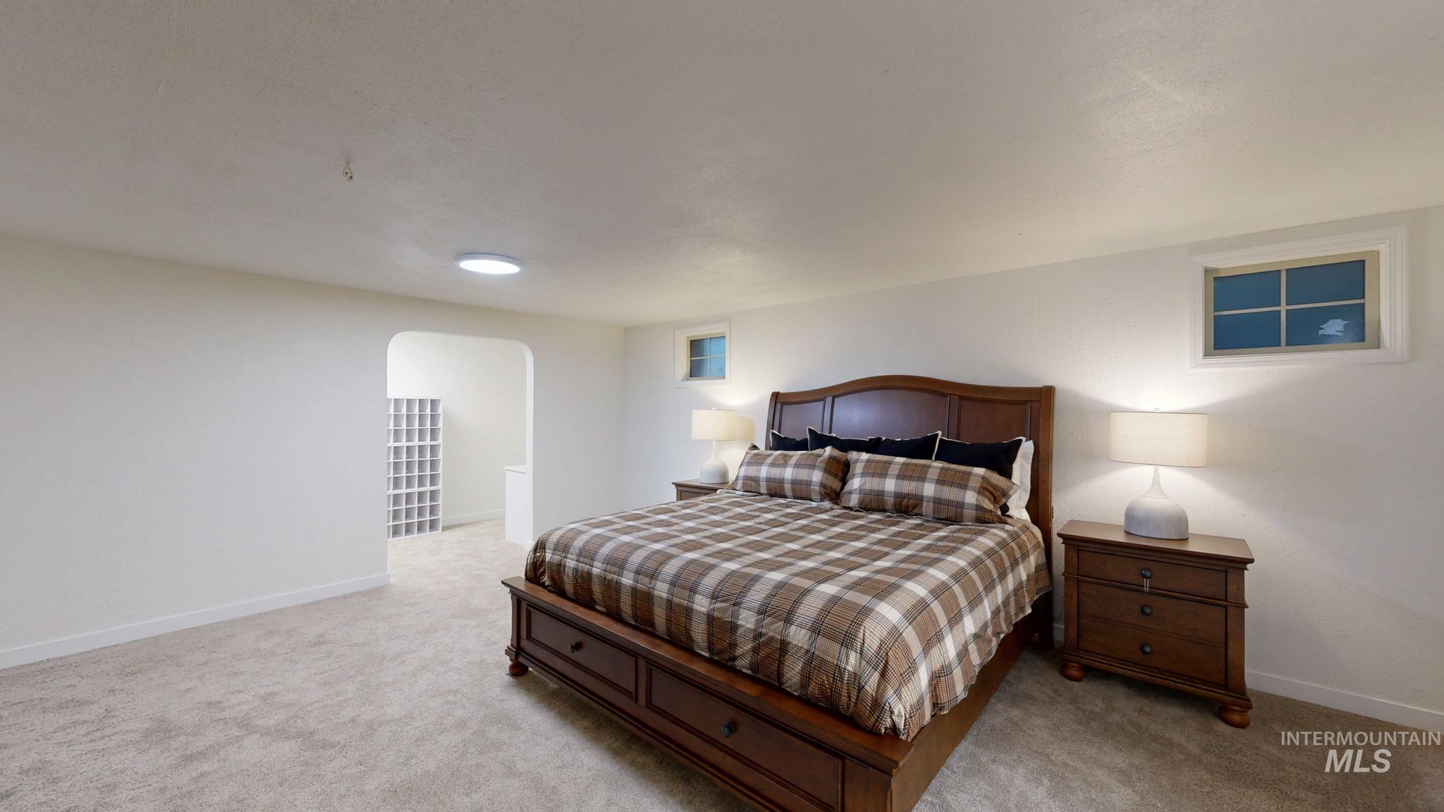 Bedroom with arched walkways and light colored carpet