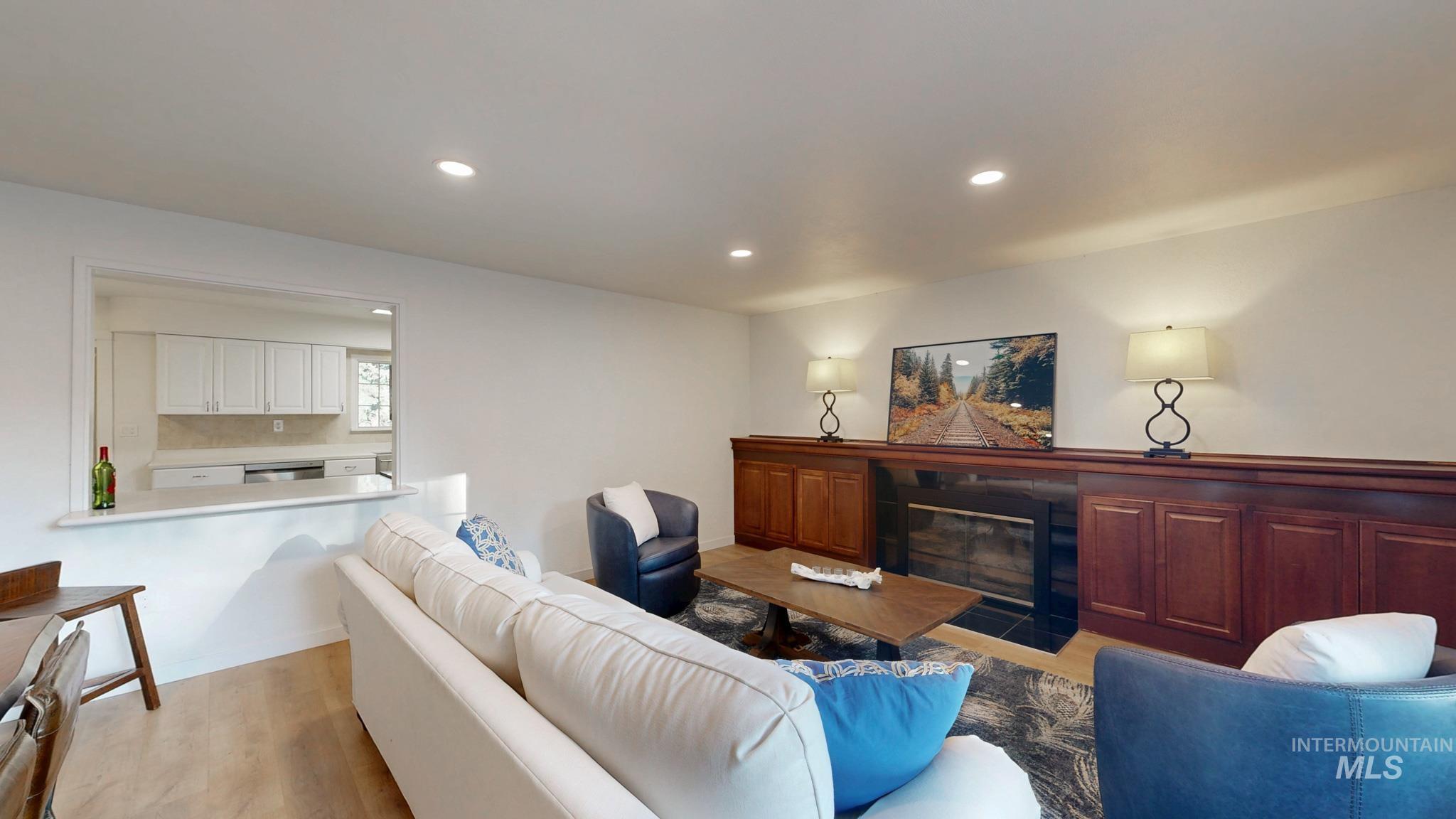 Living room with a fireplace with flush hearth, recessed lighting, and light wood finished floors
