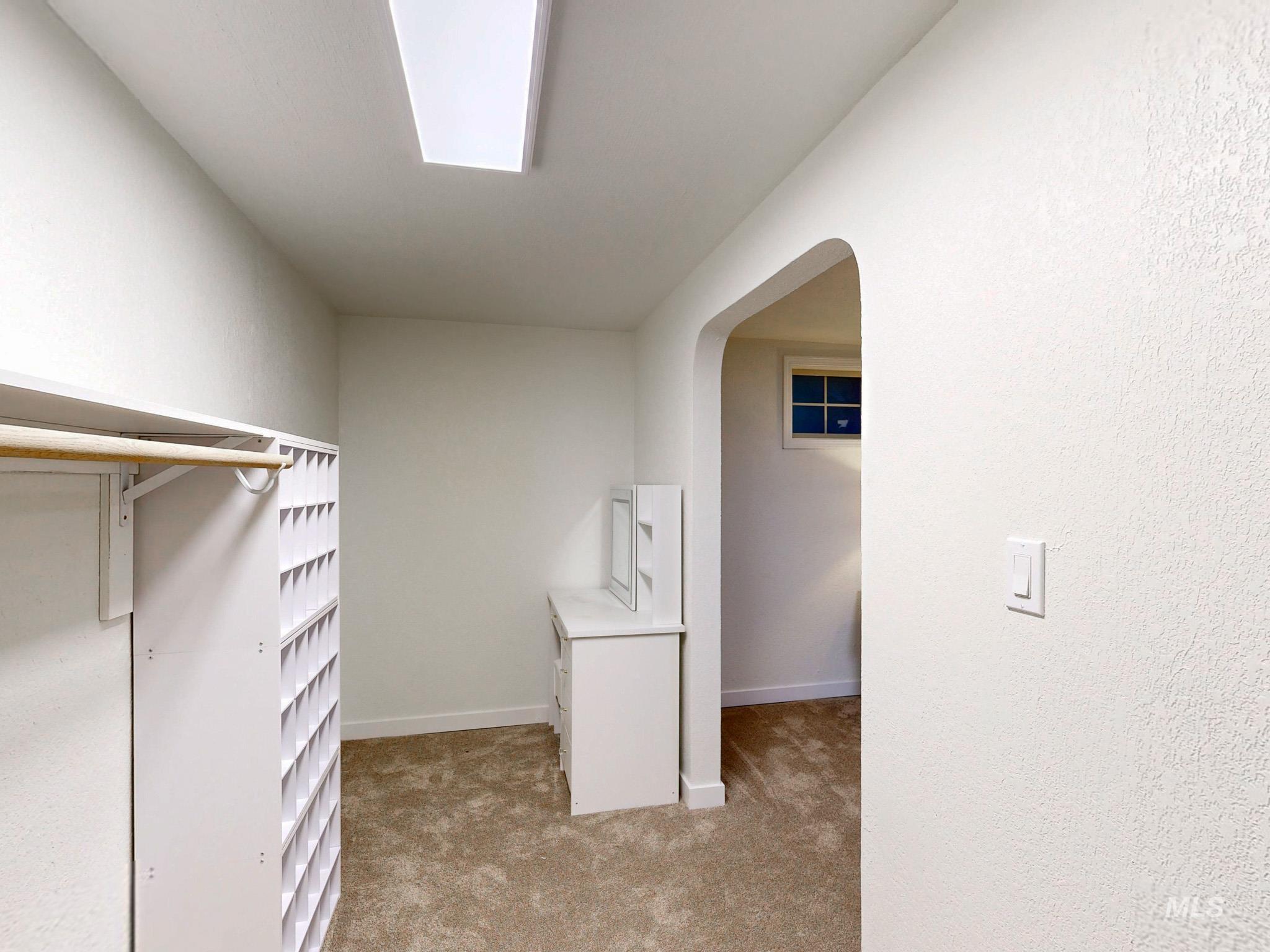 Walk in closet with light carpet and arched walkways