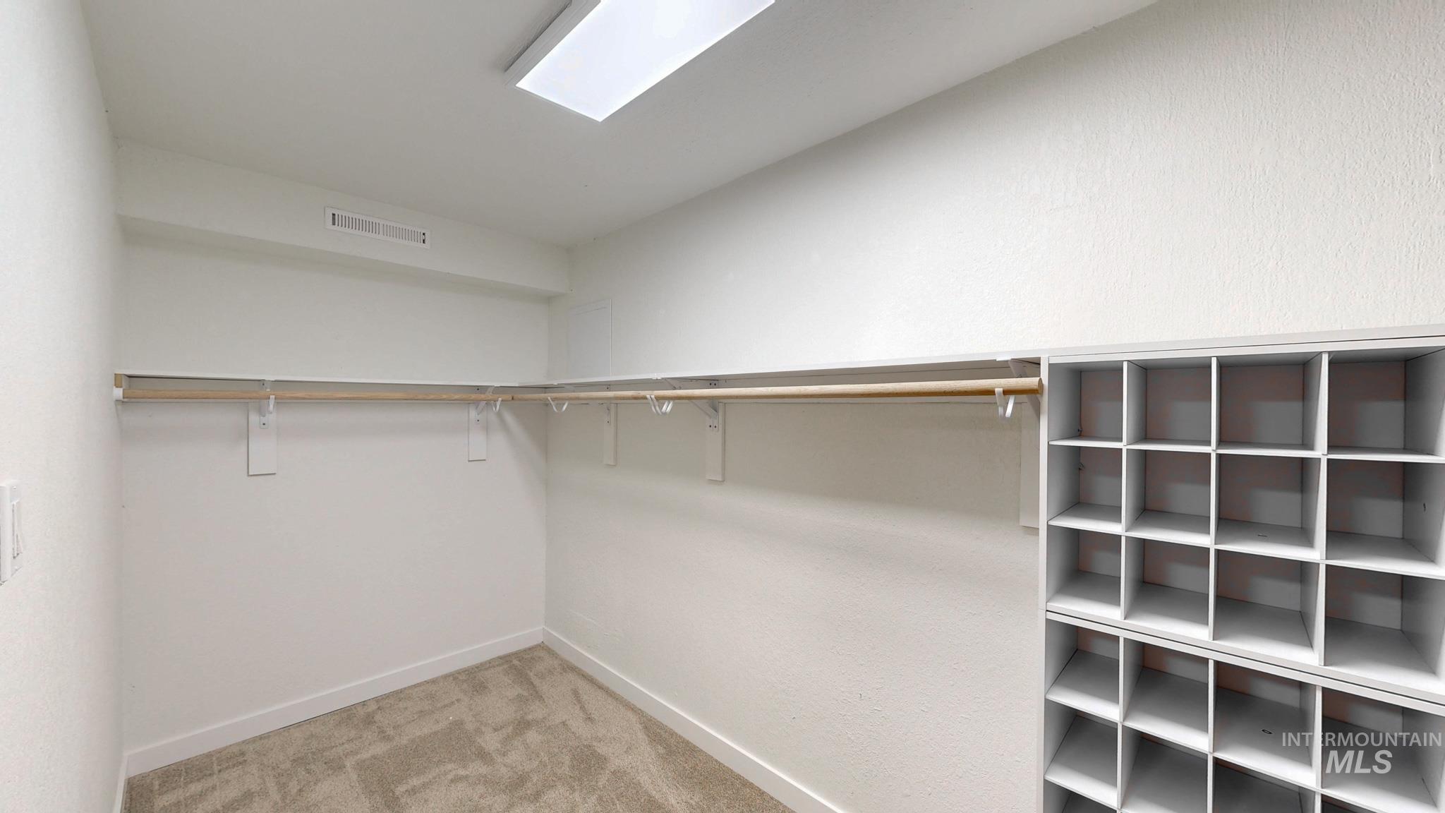 Spacious closet featuring light colored carpet