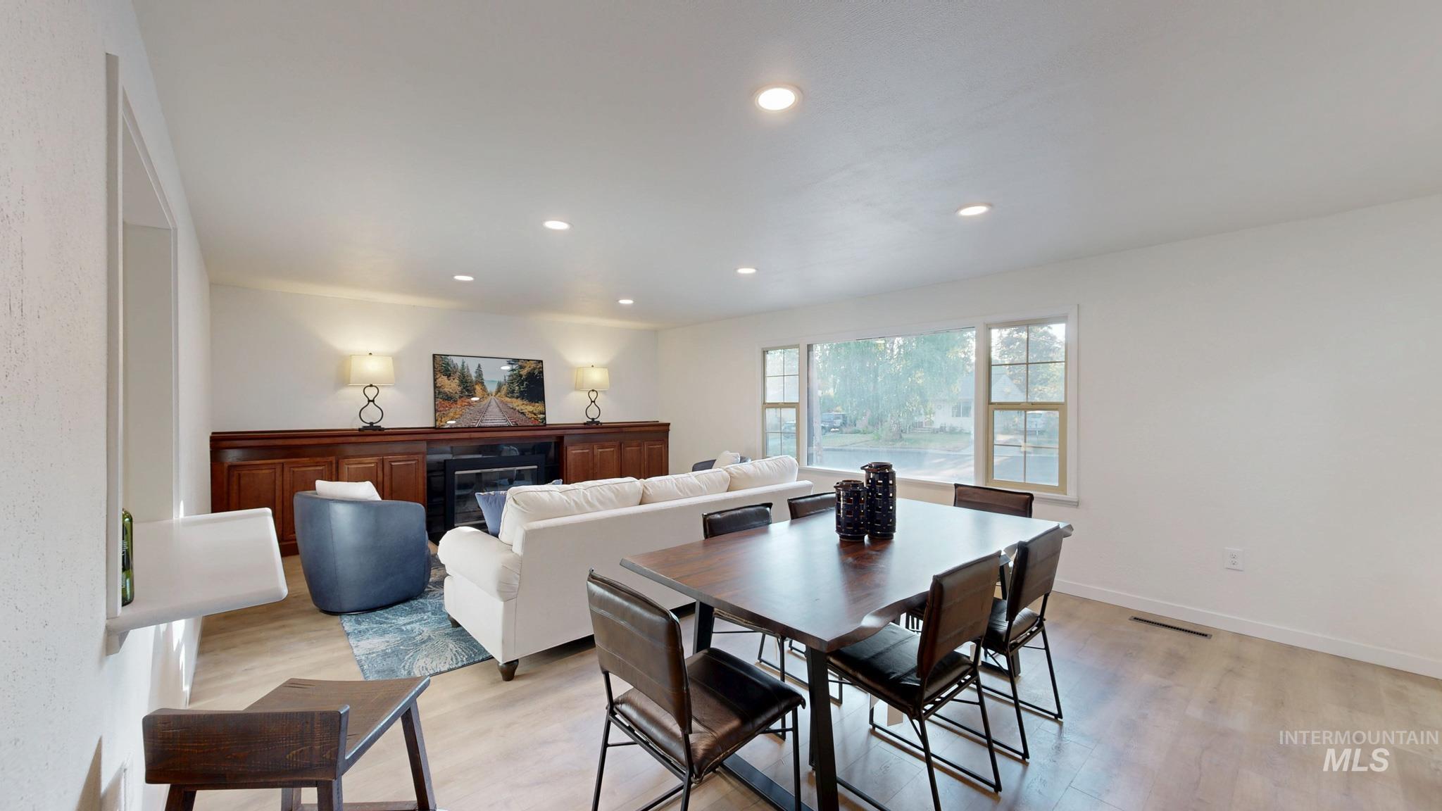 Dining space featuring light wood-type flooring, a glass covered fireplace, and recessed lighting