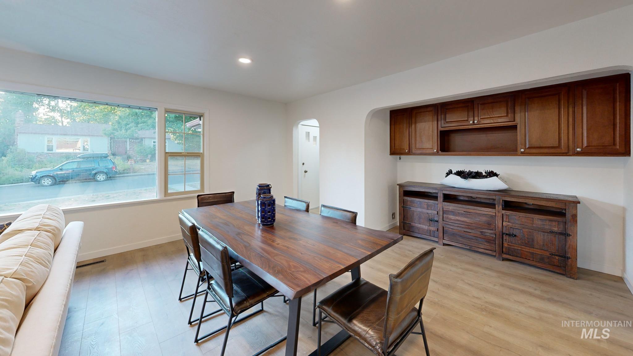 Dining space featuring light wood-type flooring, arched walkways, and recessed lighting