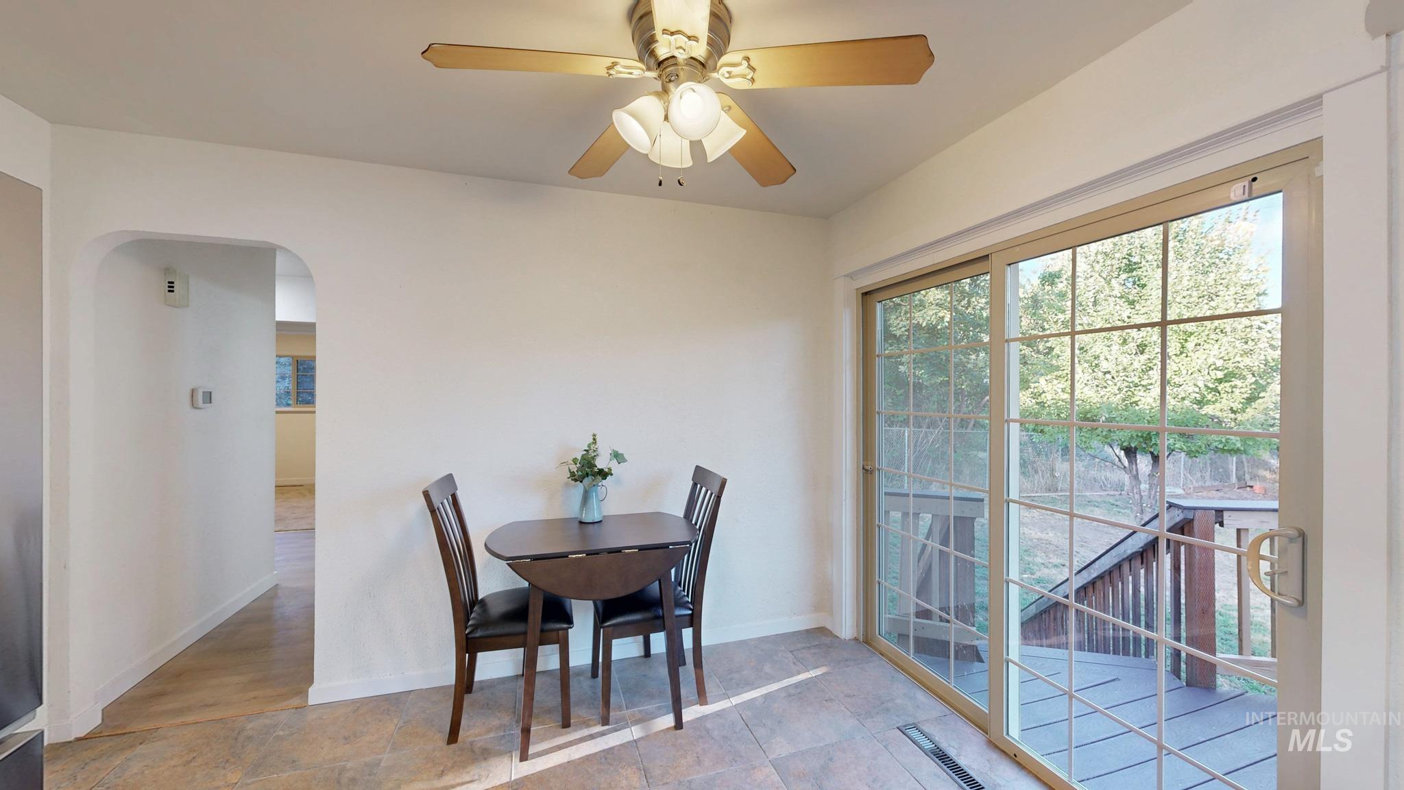 Dining area featuring arched walkways, a ceiling fan, and light stone finish flooring