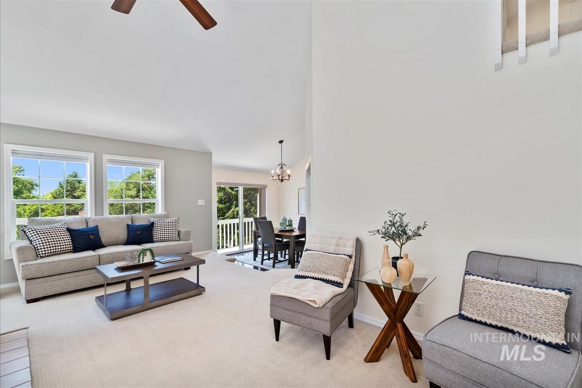 Carpeted living area with a chandelier, a ceiling fan, and a high ceiling