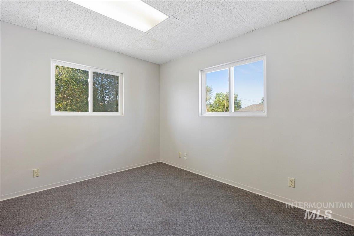 Unfurnished room featuring dark carpet and a paneled ceiling