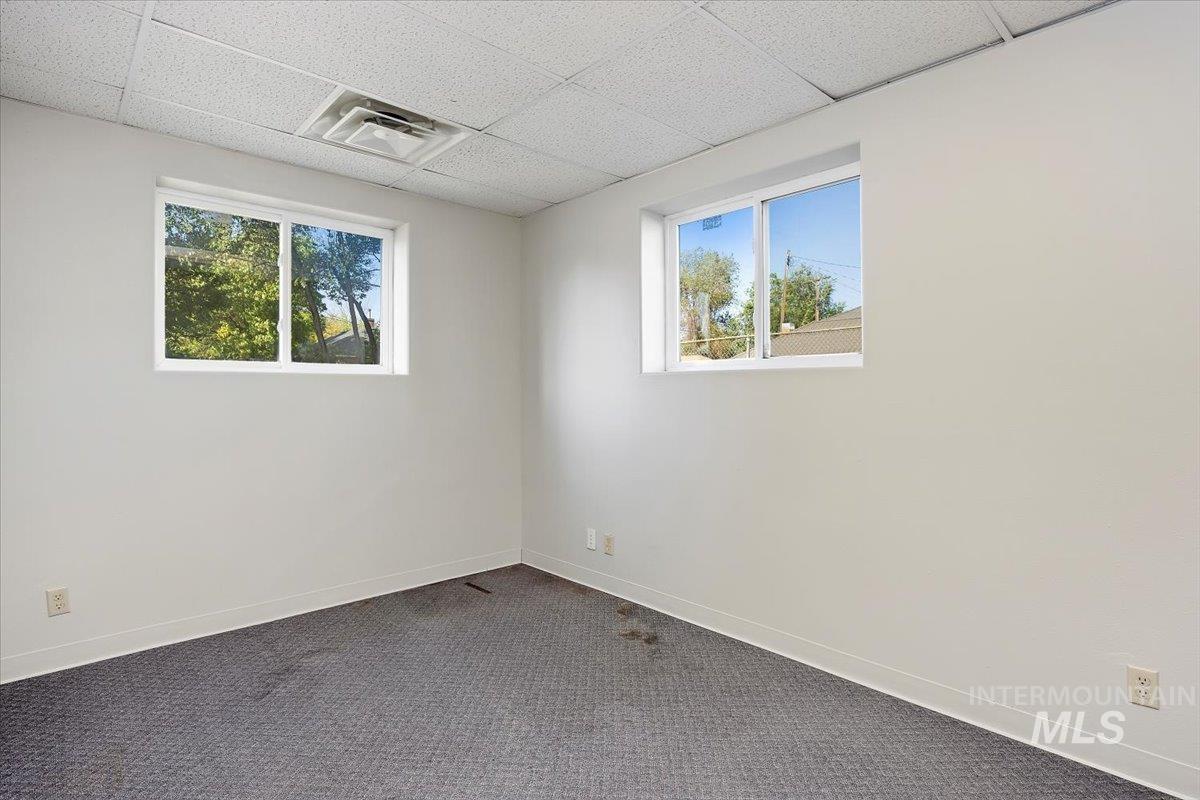 Carpeted empty room featuring a paneled ceiling and baseboards