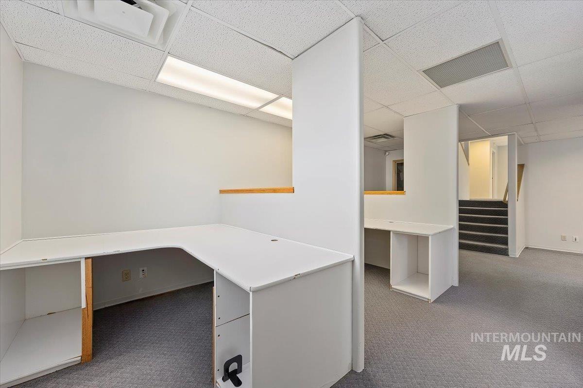 Unfurnished office with dark carpet and a drop ceiling
