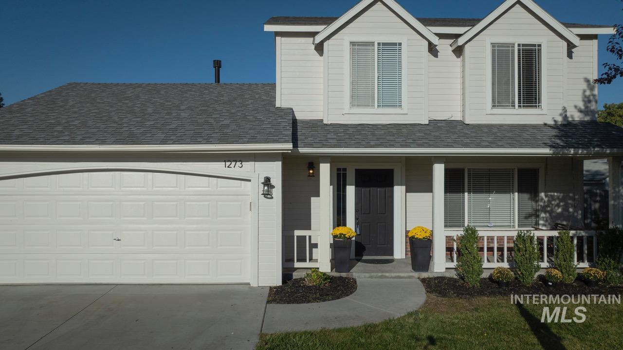 Traditional home featuring a porch, concrete driveway, an attached garage, and a shingled roof