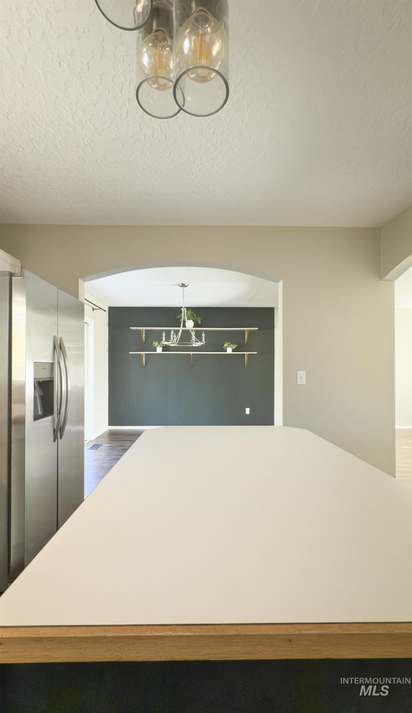 Kitchen with a chandelier, stainless steel fridge, a textured ceiling, and arched walkways