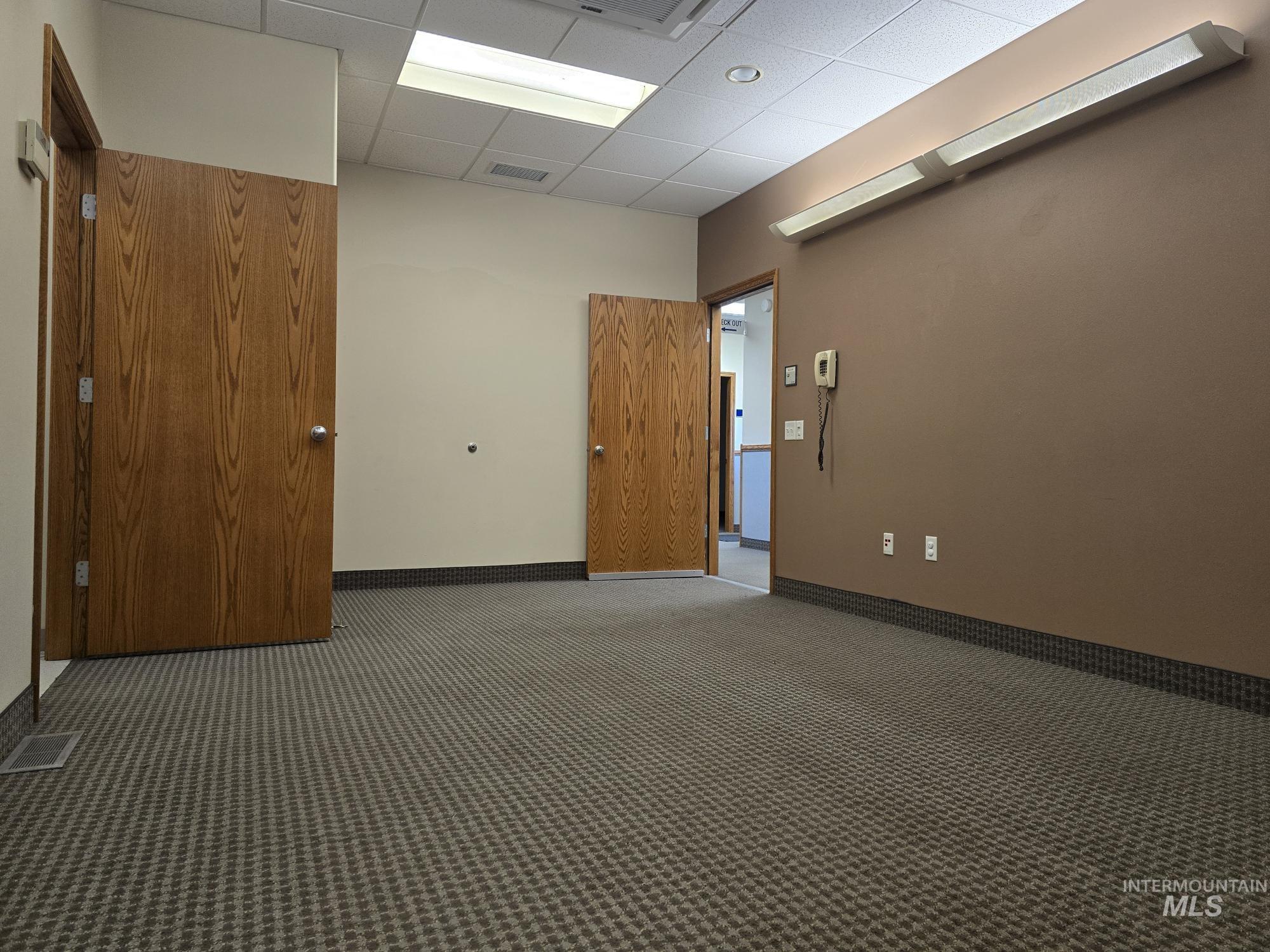 Empty room featuring a drop ceiling and carpet floors