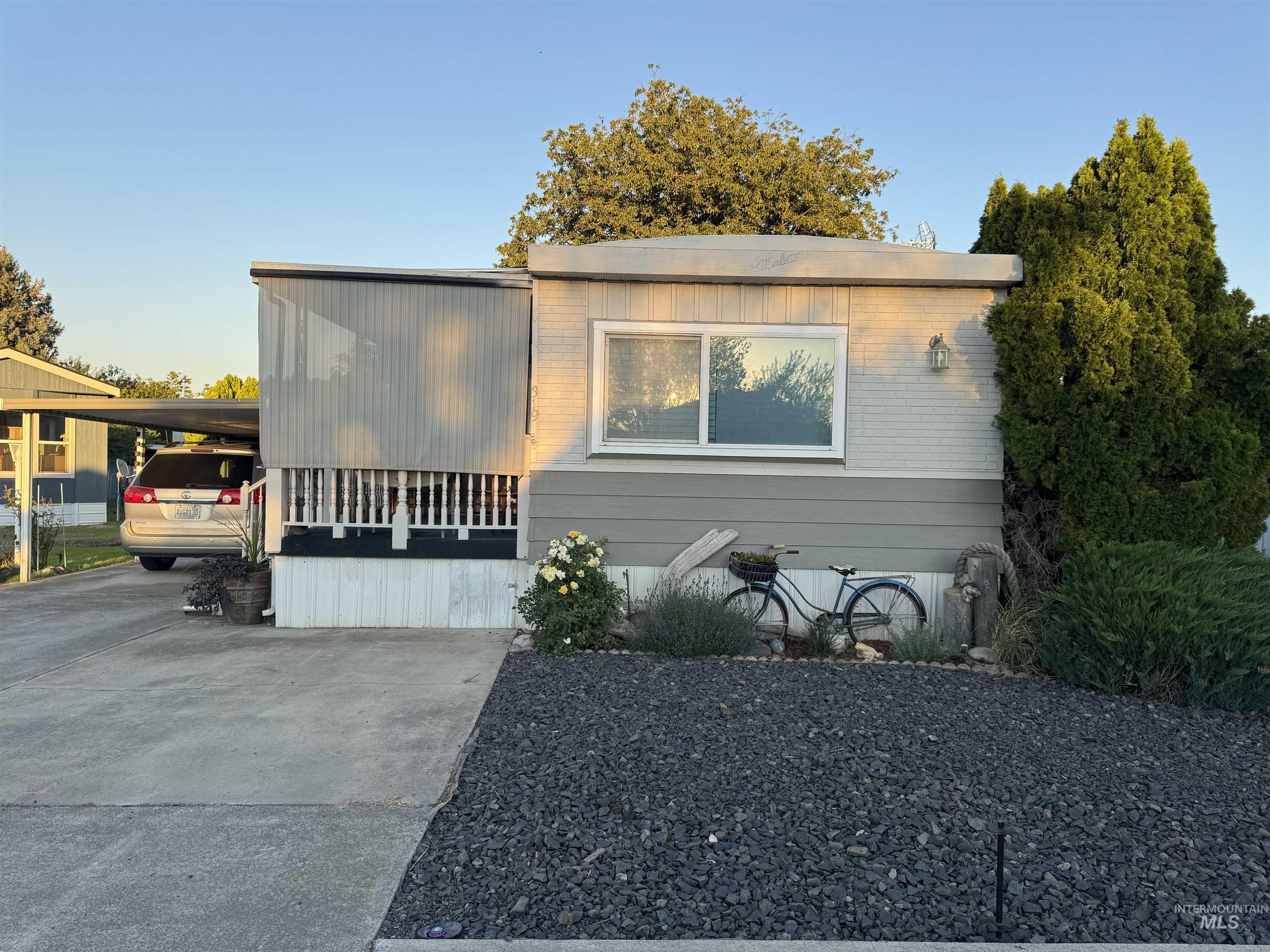Manufactured / mobile home featuring brick siding, driveway, and an attached carport