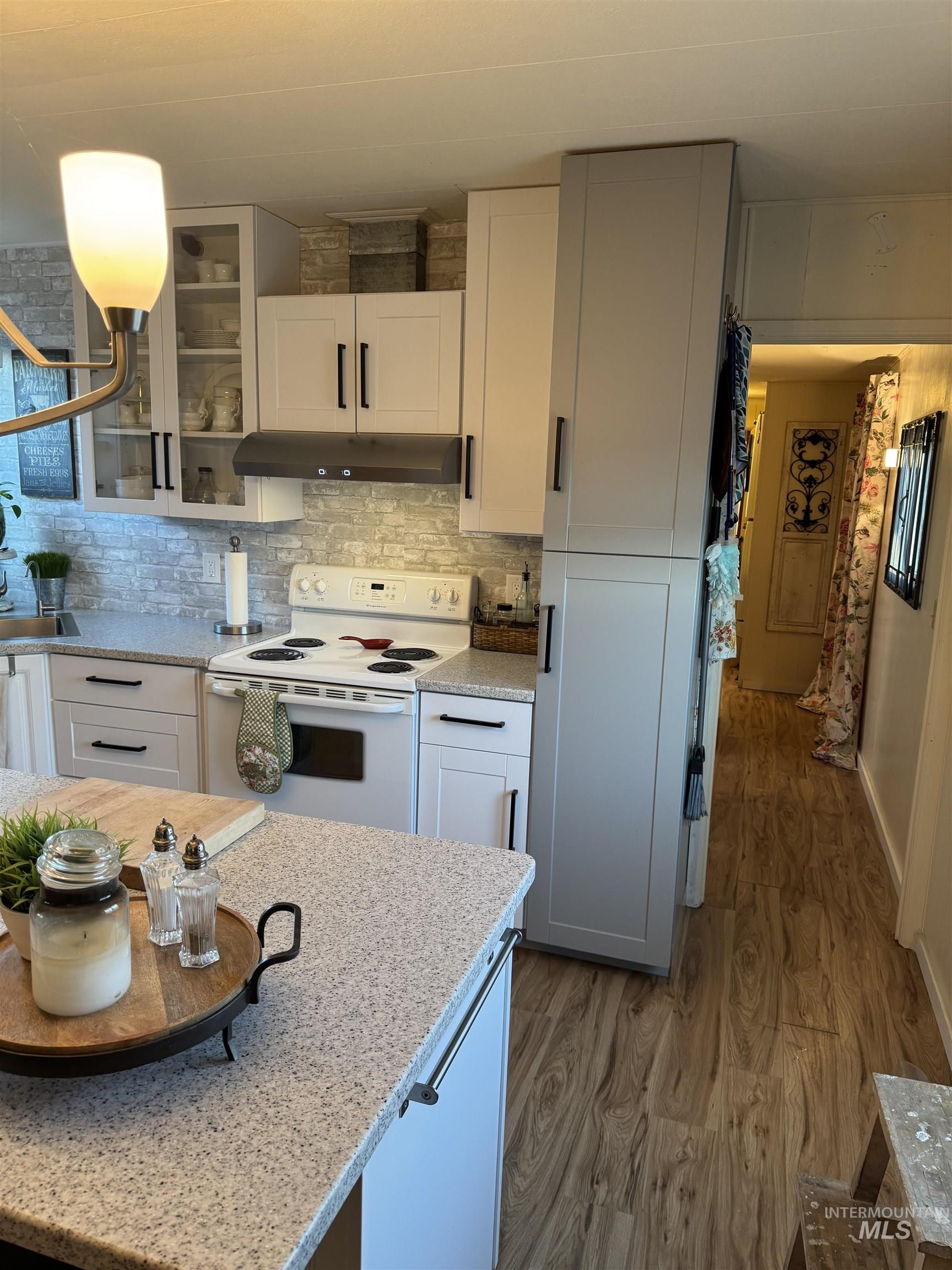 Kitchen with white cabinets, white range with electric stovetop, and light stone countertops