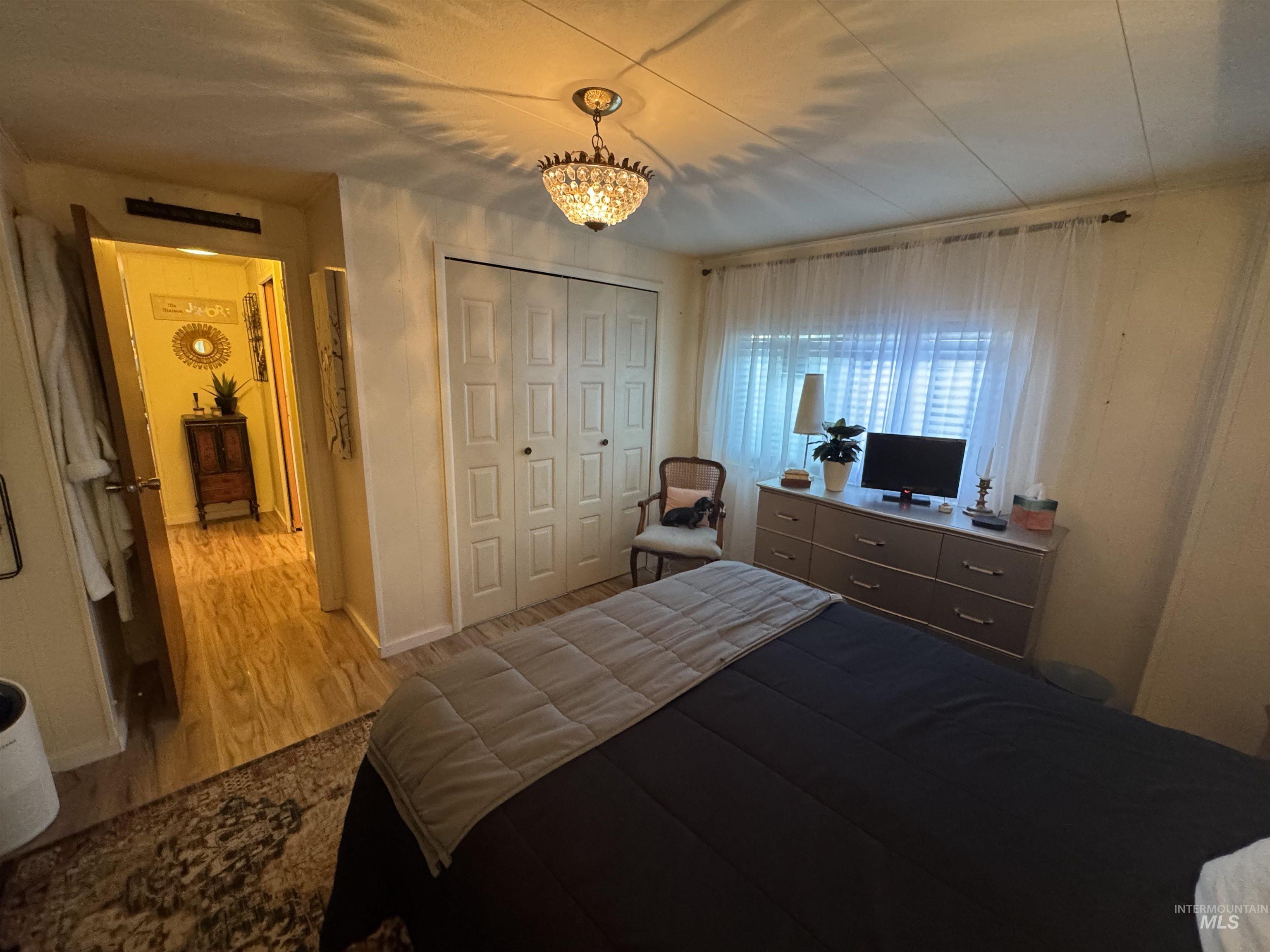 Bedroom with wood finished floors, a closet, and a chandelier