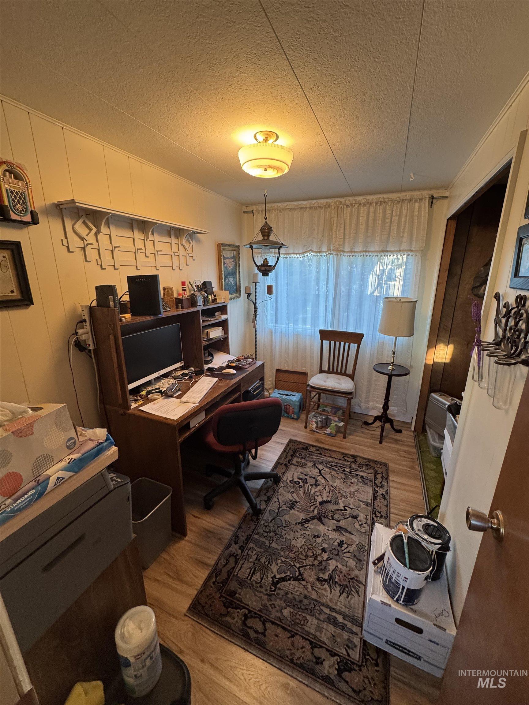 Office space featuring light wood-style flooring and a textured ceiling