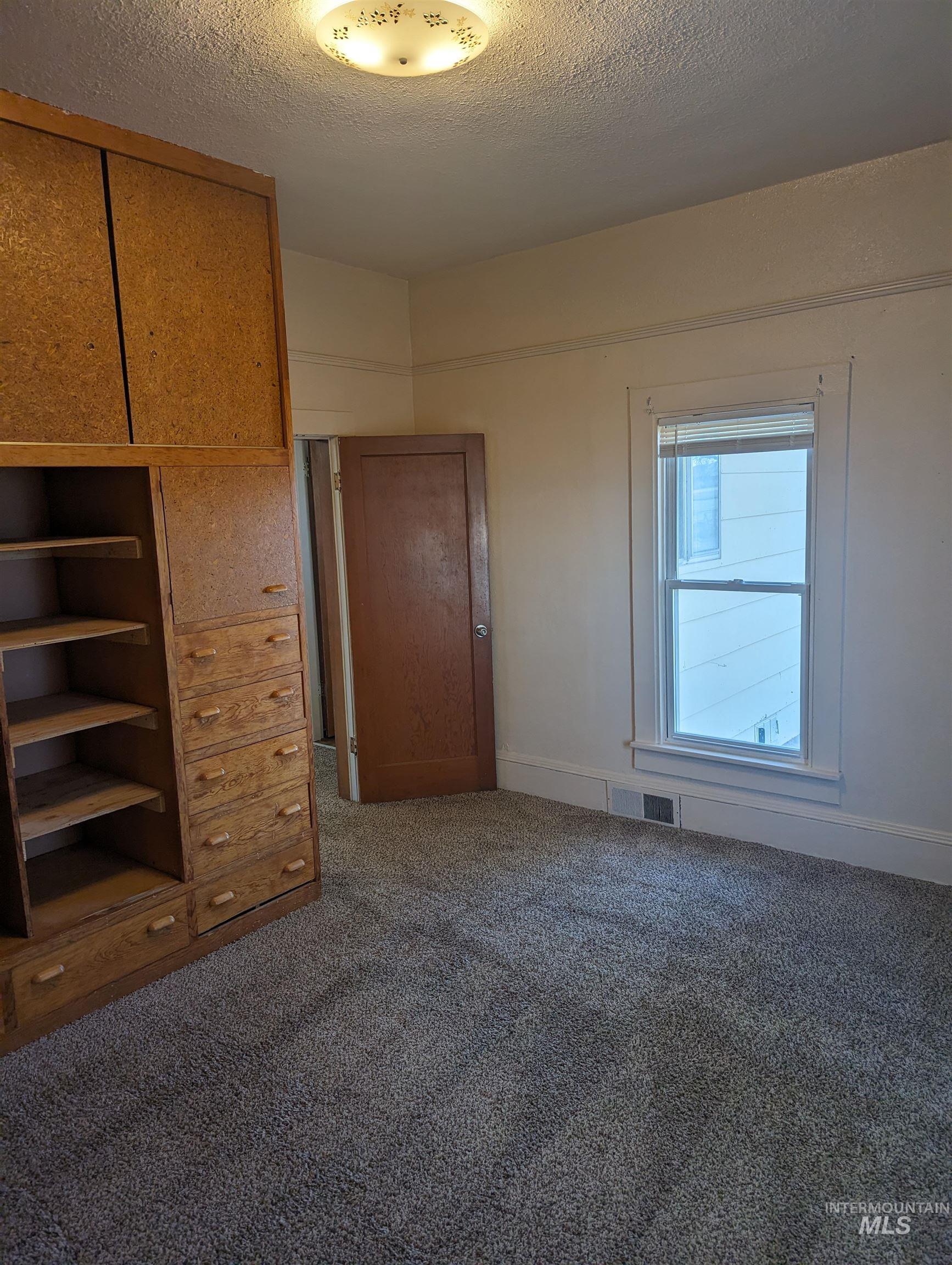 Unfurnished bedroom featuring a textured ceiling and dark colored carpet